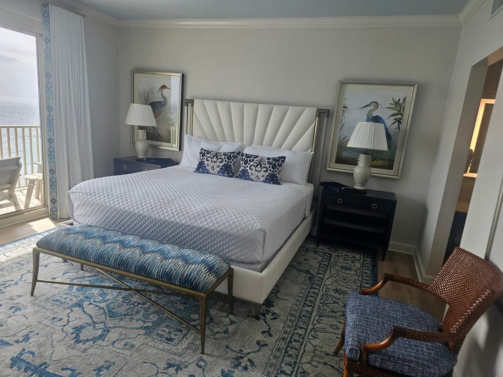 Beautifully made bed in a sunlit beachfront bedroom — coastal blue and white styling