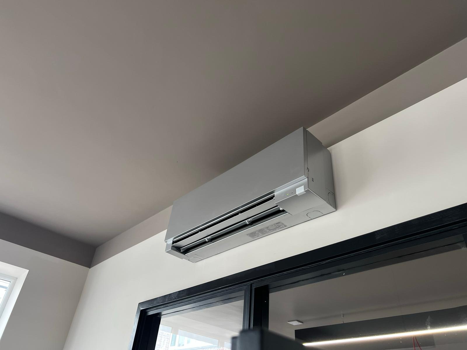 Silver wall-mounted split AC above patio doors