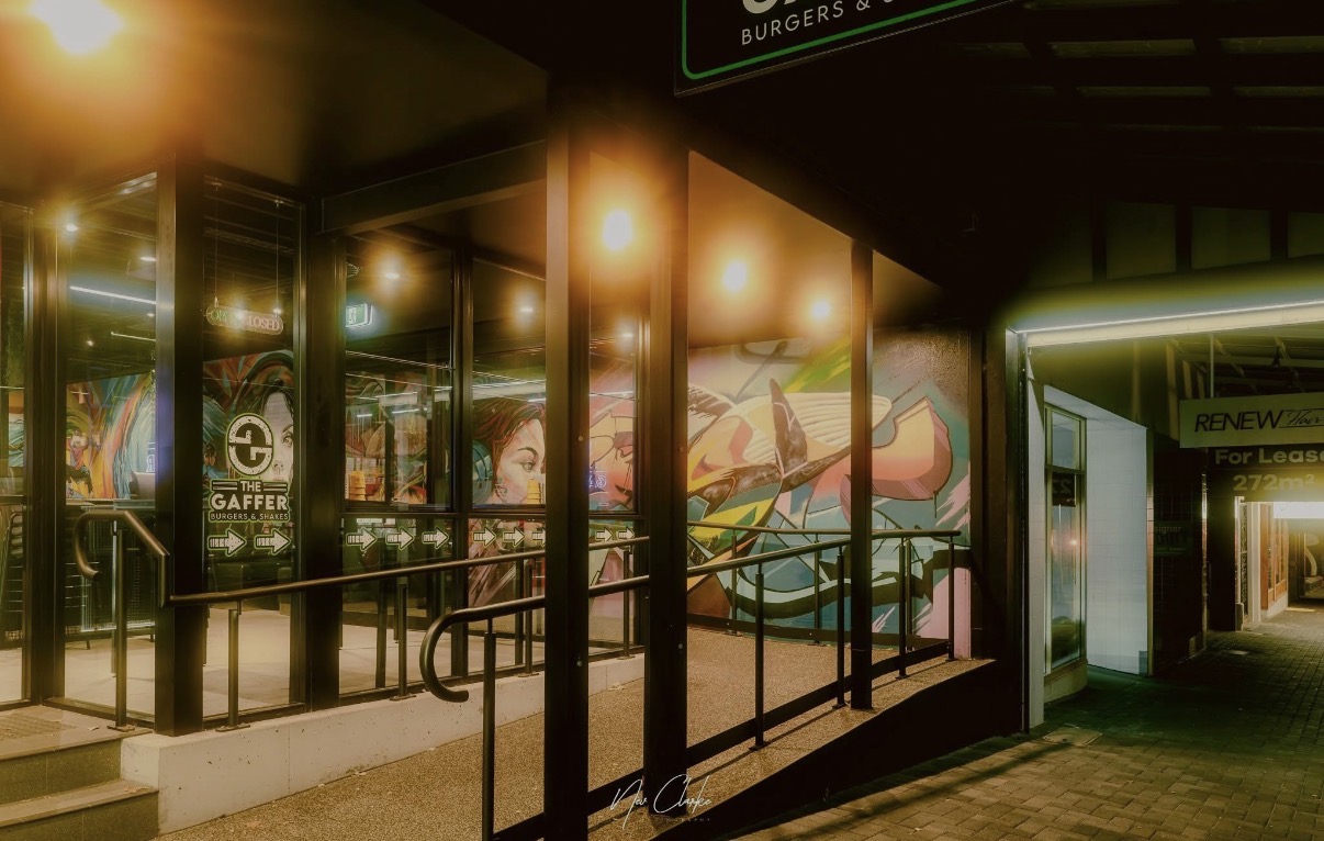 The Gaffer storefront at night — neon sign and mural-covered interior glowing through the glass