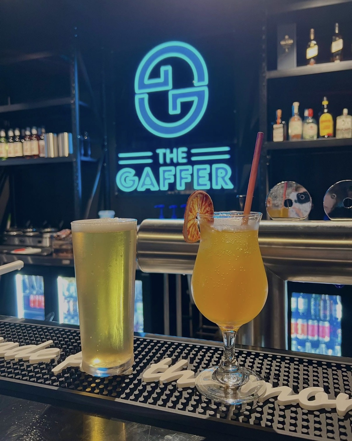 The Gaffer neon sign behind a beer and cocktail at the bar