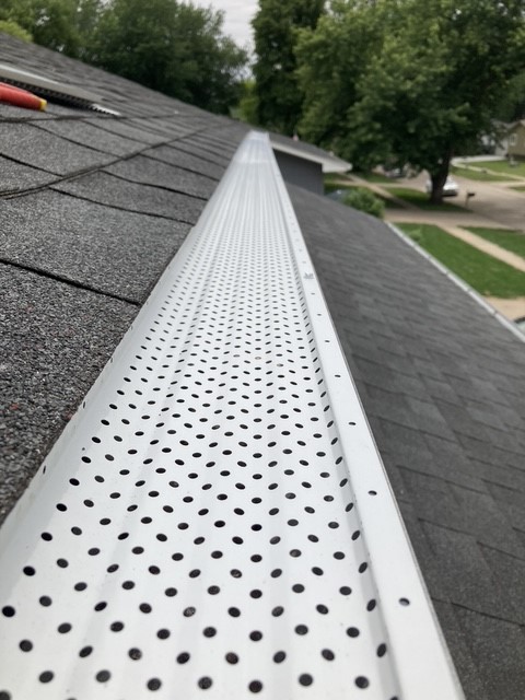White perforated gutter guards installed along a Glenwood home's roofline
