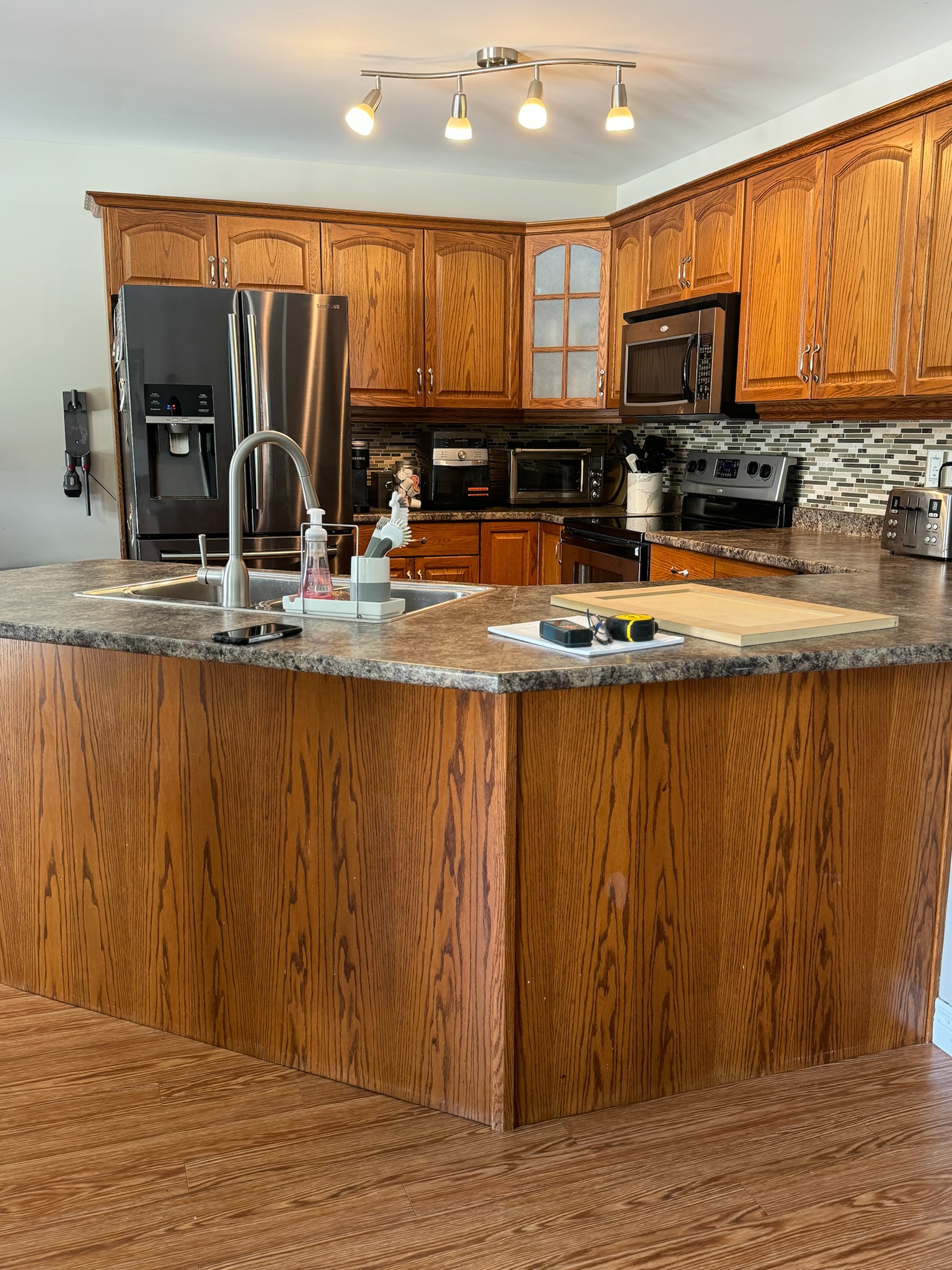 Before refinish — Cathedral oak → warm greige shaker · cabinetry extended to the ceiling