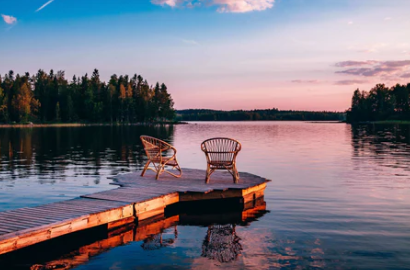 Sunset on an Ontario lake — two chairs on a wooden dock, water reflecting pink sky and pine trees