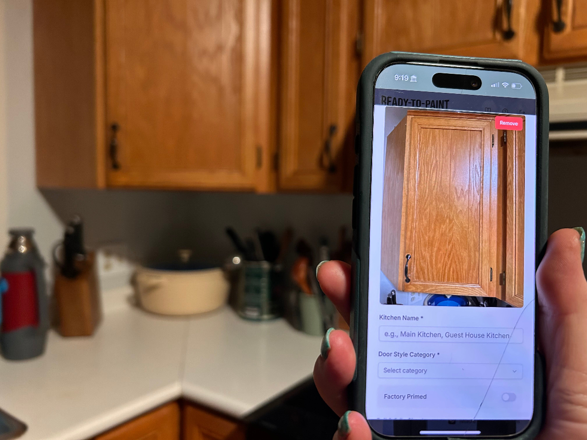 Cabinet refinisher photographing an oak cabinet door on site using the CabinetDoors.app measuring app