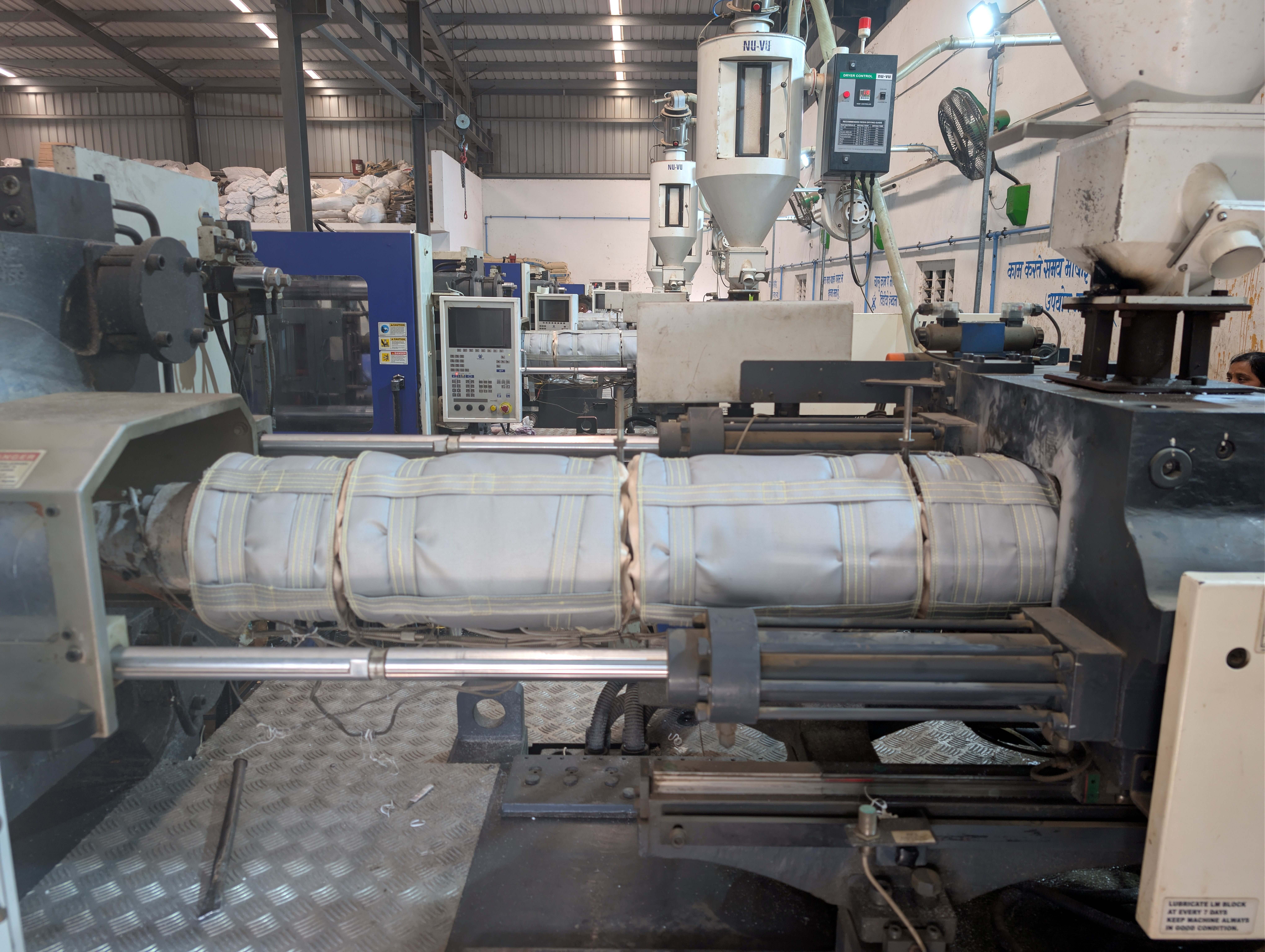 Multi-zone i-Wrap insulation jacket installed on injection molding machine barrel with yellow-stitched jacket detail