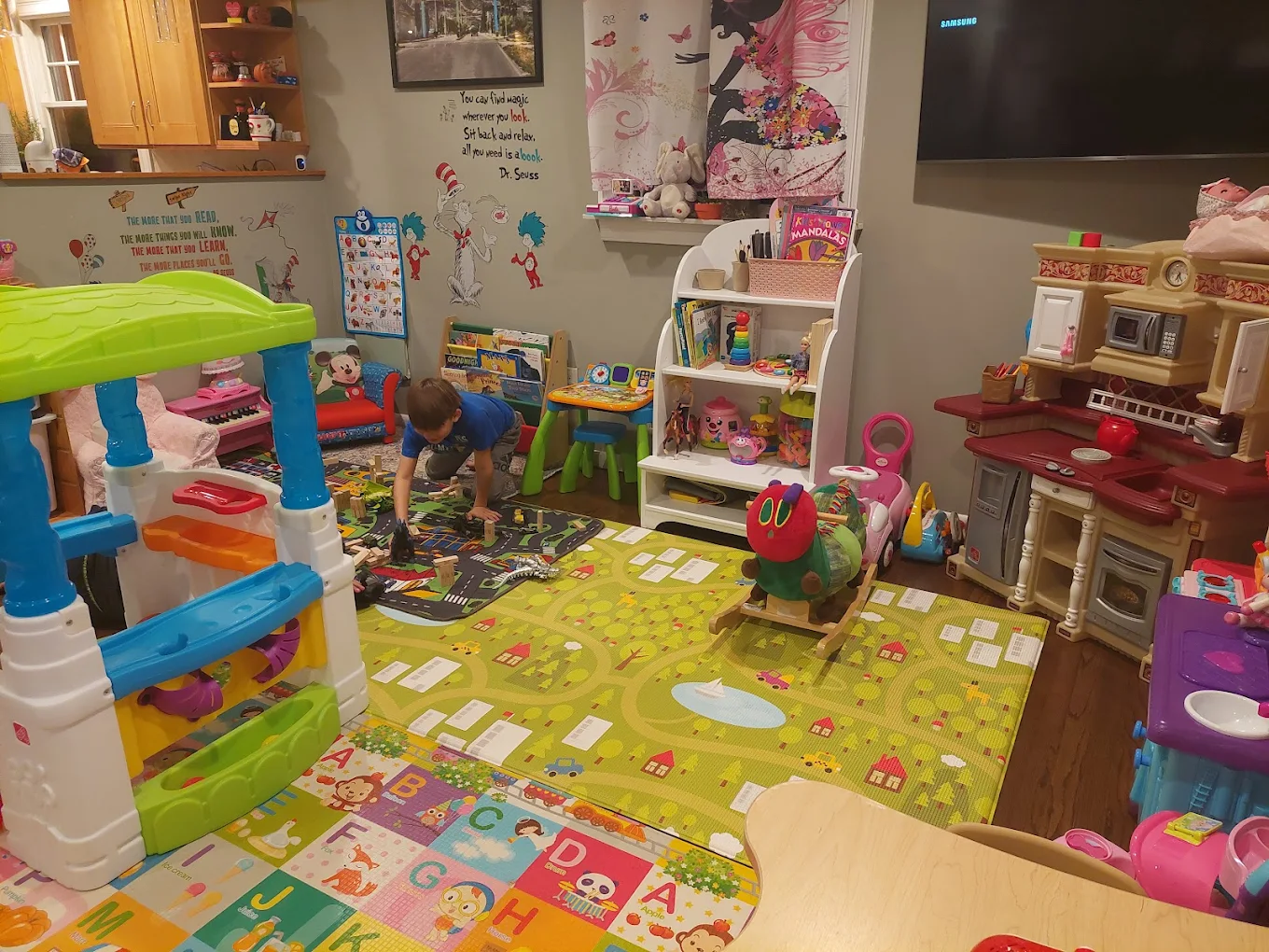 Wide view of playroom with alphabet mat, kitchen playset and toys