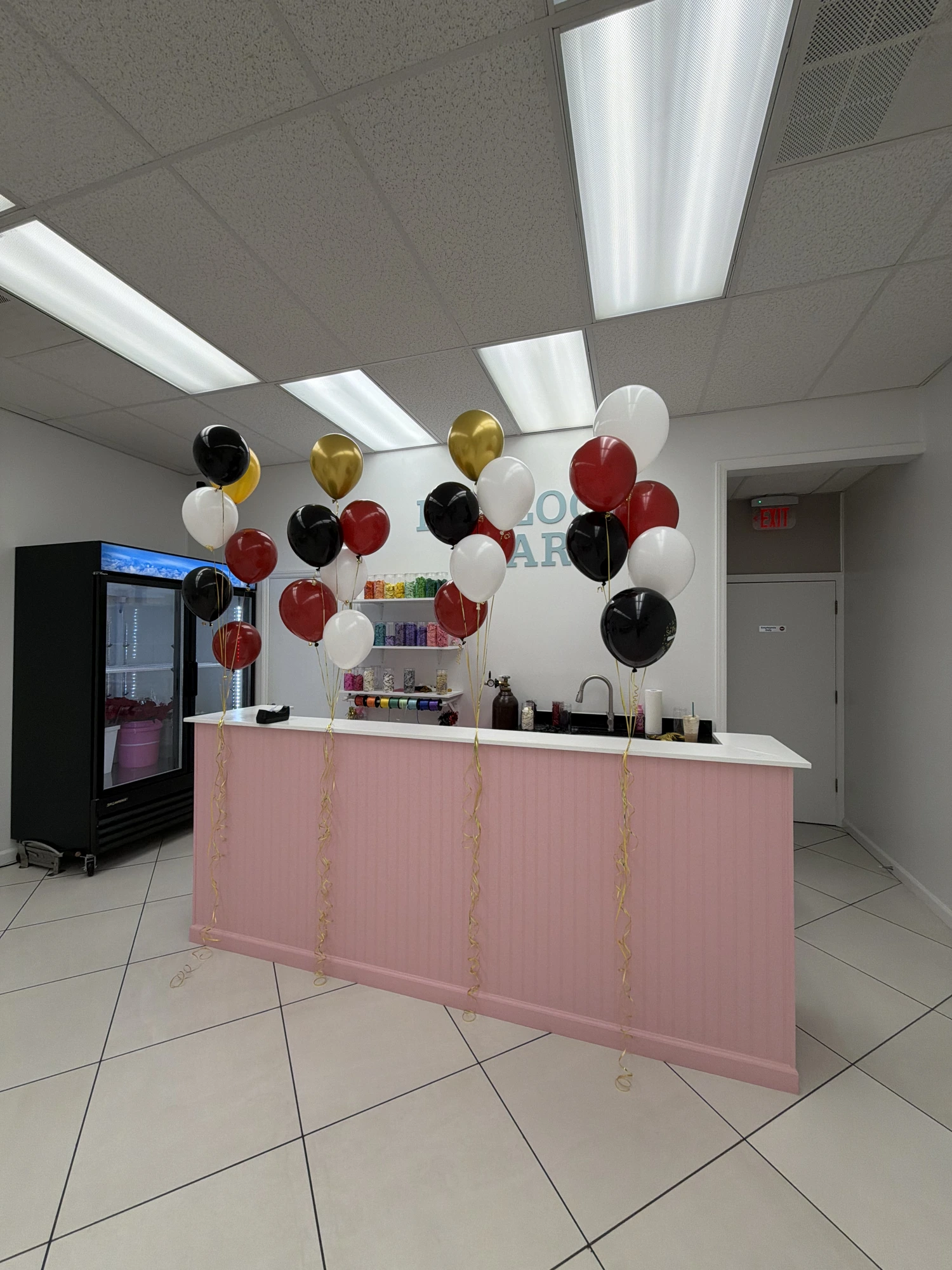 Red, black, gold and white balloon bouquets over pink counter