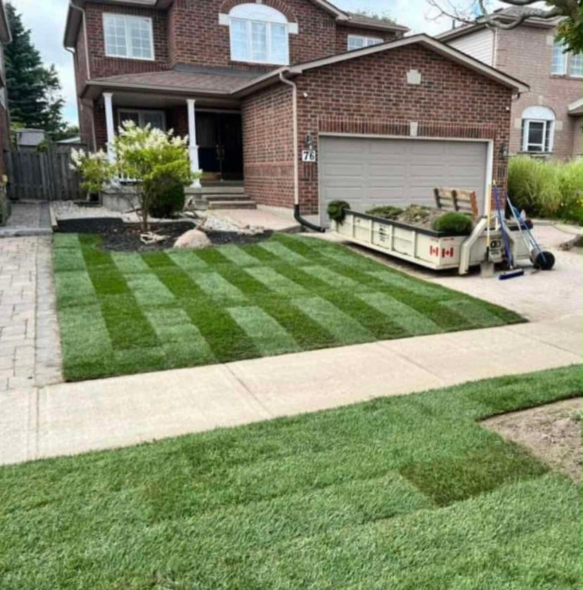Front yard sod installation with striped finish and a debris trailer parked at curbside