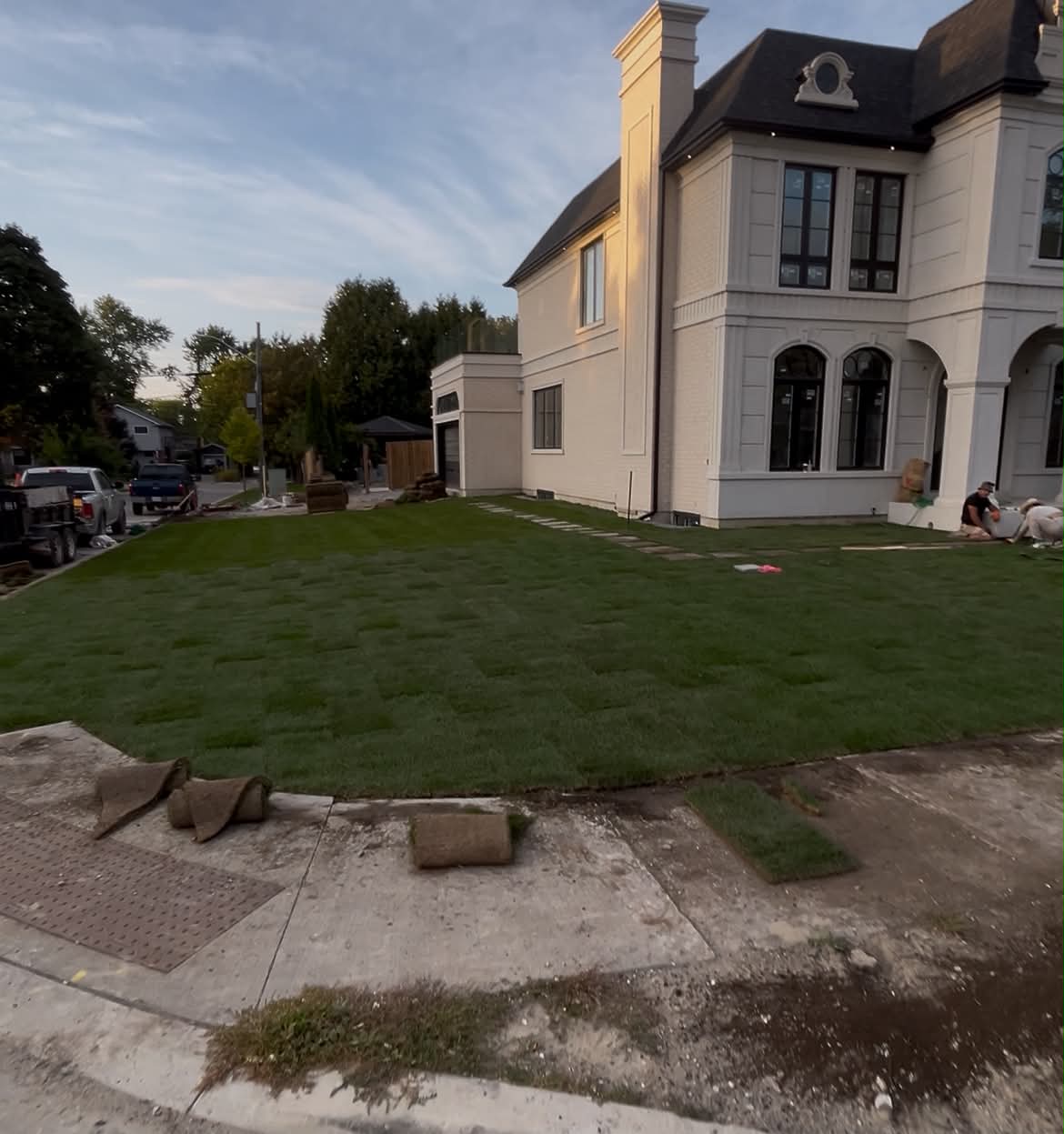 Estate-style home with a freshly installed sod lawn and stone walkway at golden hour