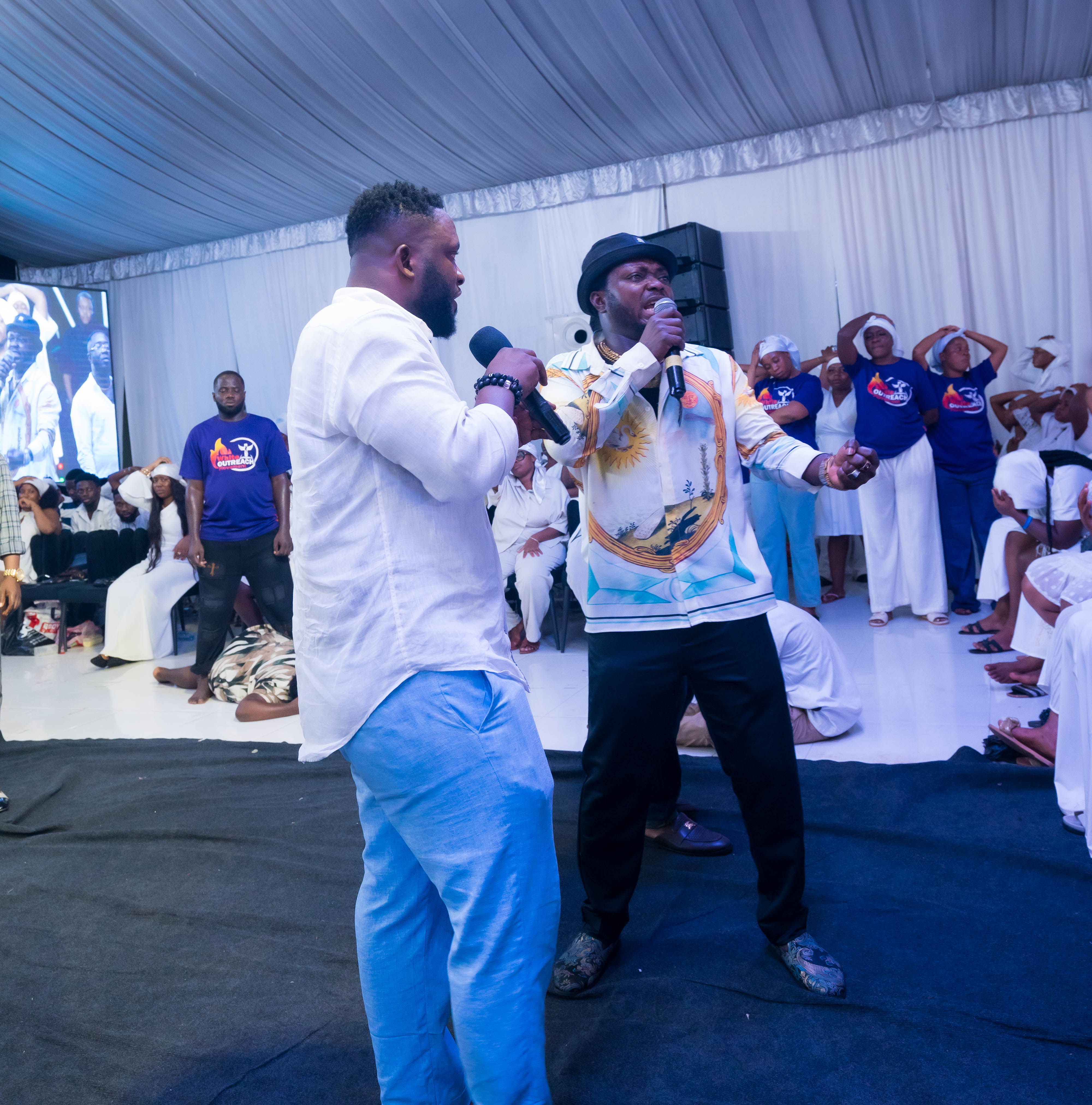 Pastor White seated on stage with ministers and worshippers during a White Outreach service