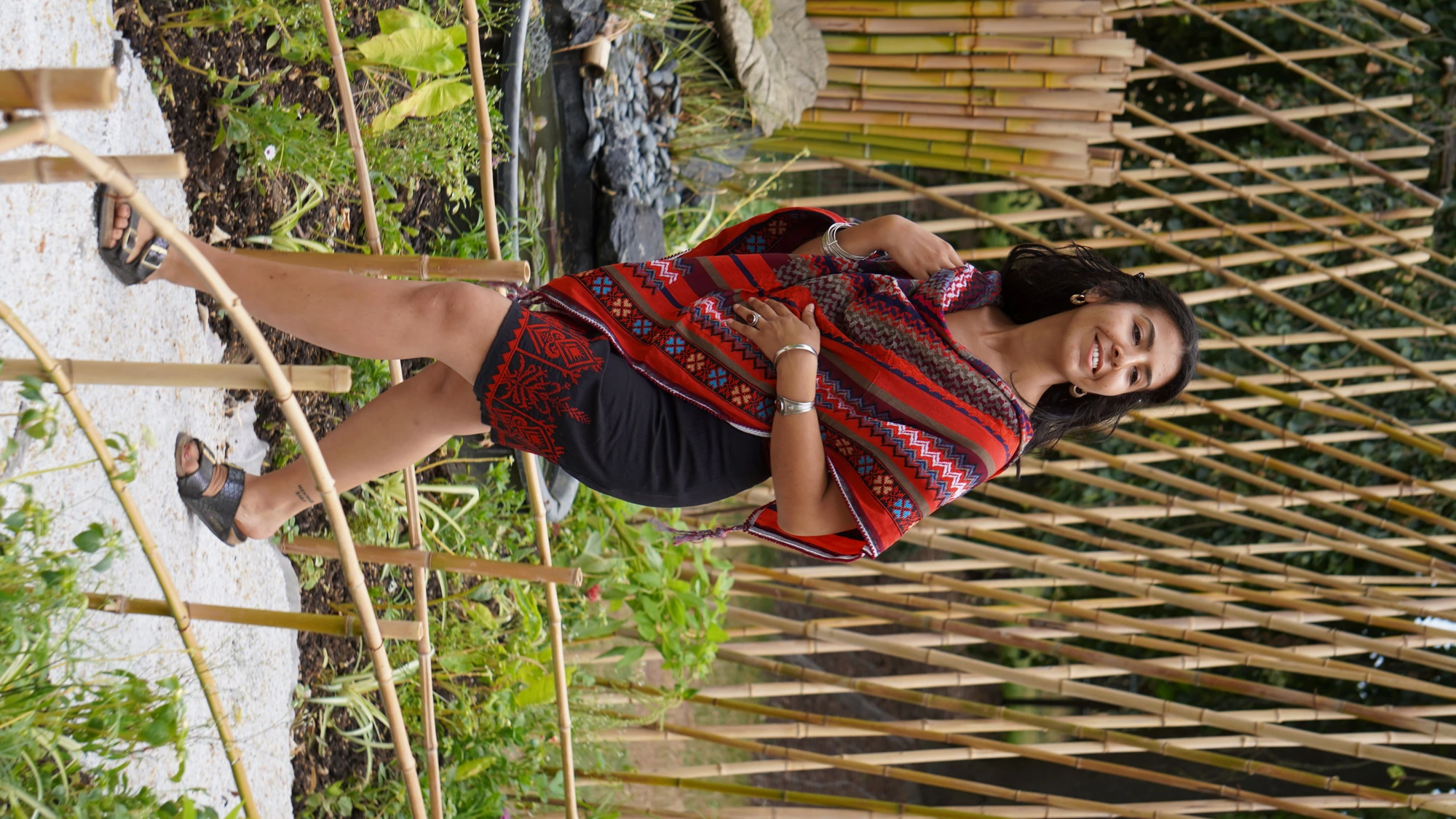 Femme portant un châle brodé Levami à motifs traditionnels colorés dans un jardin.