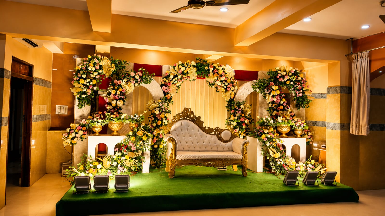 Golden ceremony stage with ivory throne and floral arches