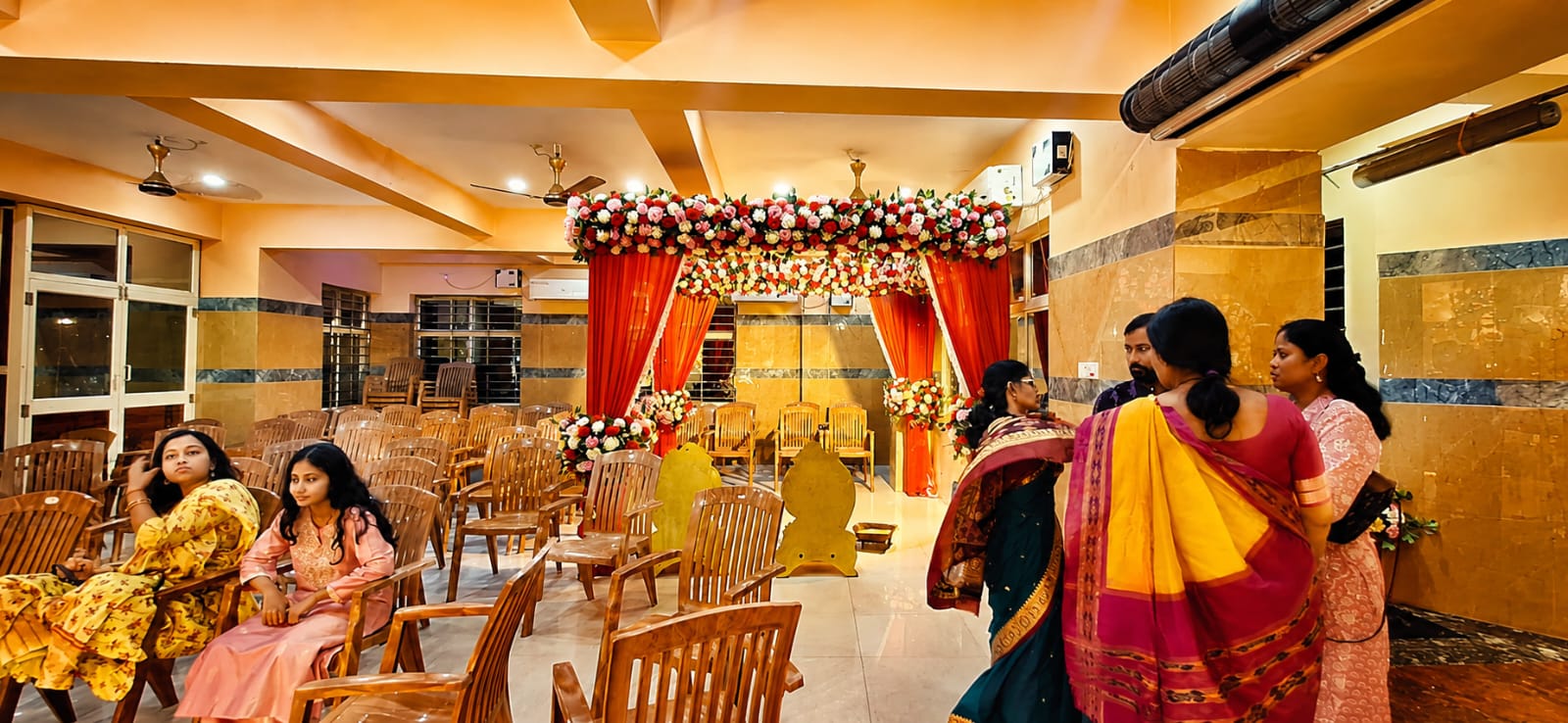 Family gathered before the floral red mandap for the ceremony