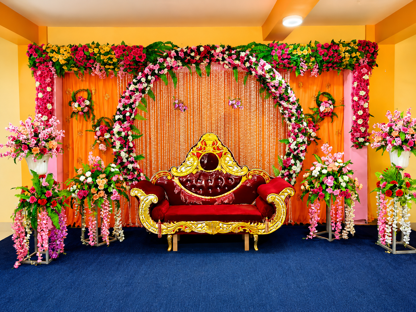 Royal red & gold wedding throne with floral mandap backdrop