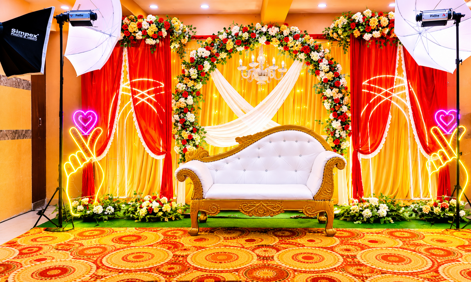 Golden floral mandap with white throne, chandelier and neon heart accents