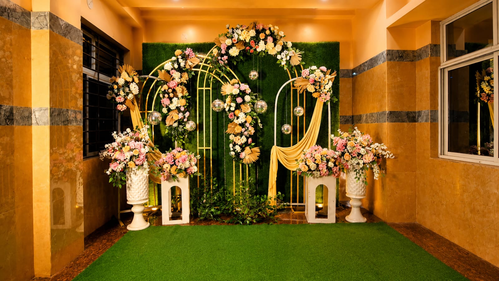 Pastel floral archway with grass-wall backdrop and pedestal blooms