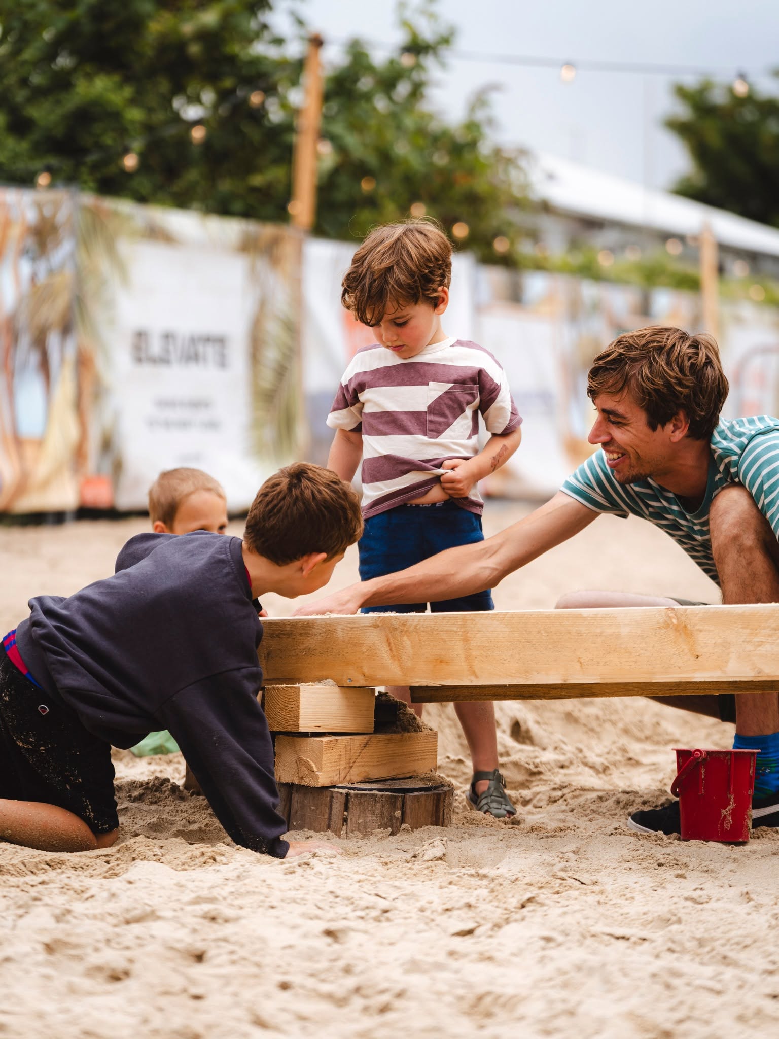 Kinderen geven een high-five aan de Mechelen Beach mascotte op het zand