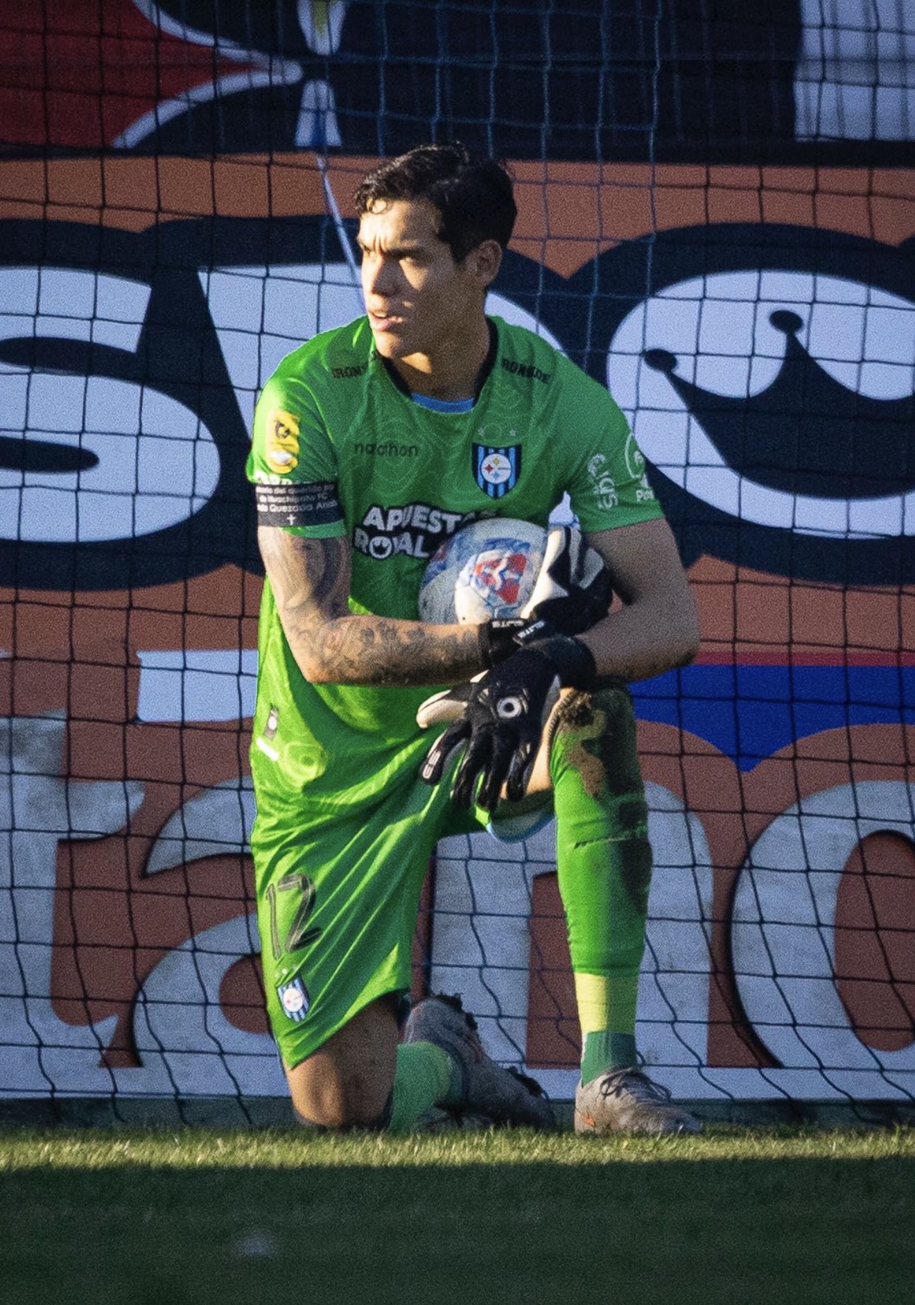 Christian Bravo concentrado apoyado en poste - Uniforme verde Huachipato