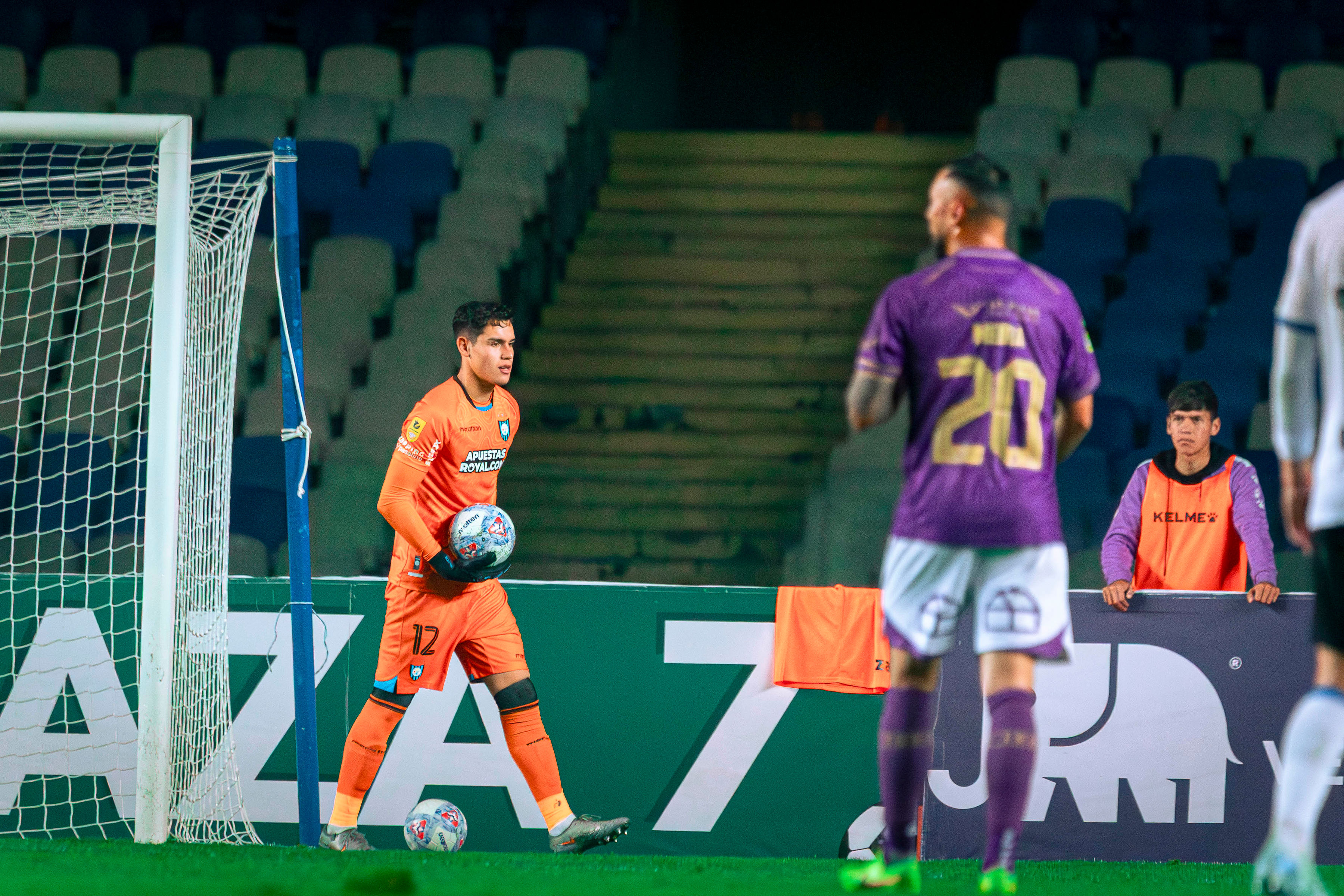 Christian Bravo sosteniendo balón en acción de juego - Uniforme naranja Huachipato