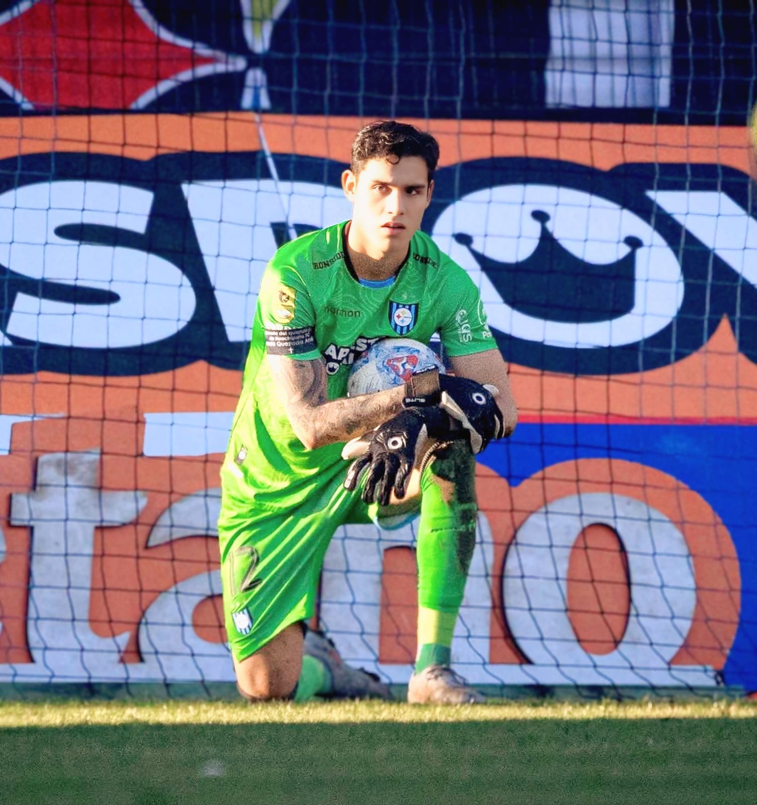 Christian Bravo de rodillas con balón - Mirada intensa uniforme verde Huachipato