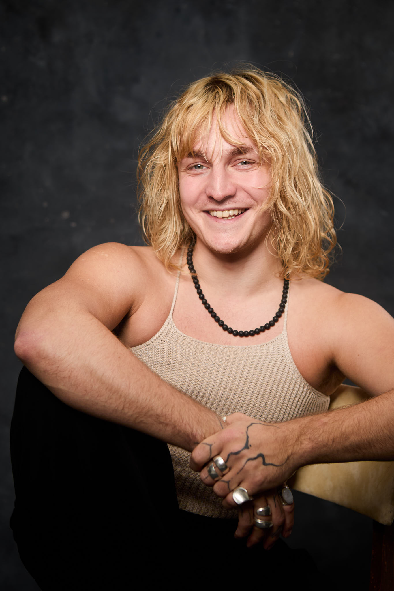 Colour studio headshot — blonde curly hair, warm smile, beaded necklace — shot at Peanut Factory Studio, Hackney Wick