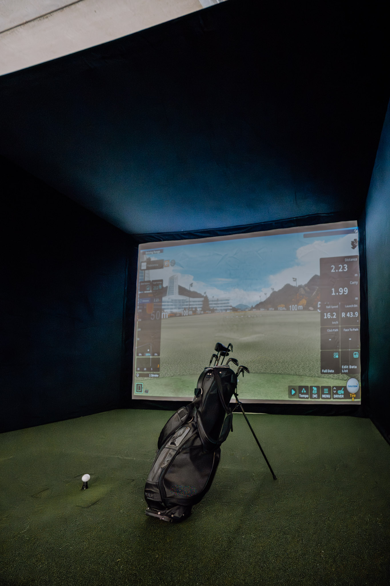 Golf simulator booth with clubs and tee at Padelarena