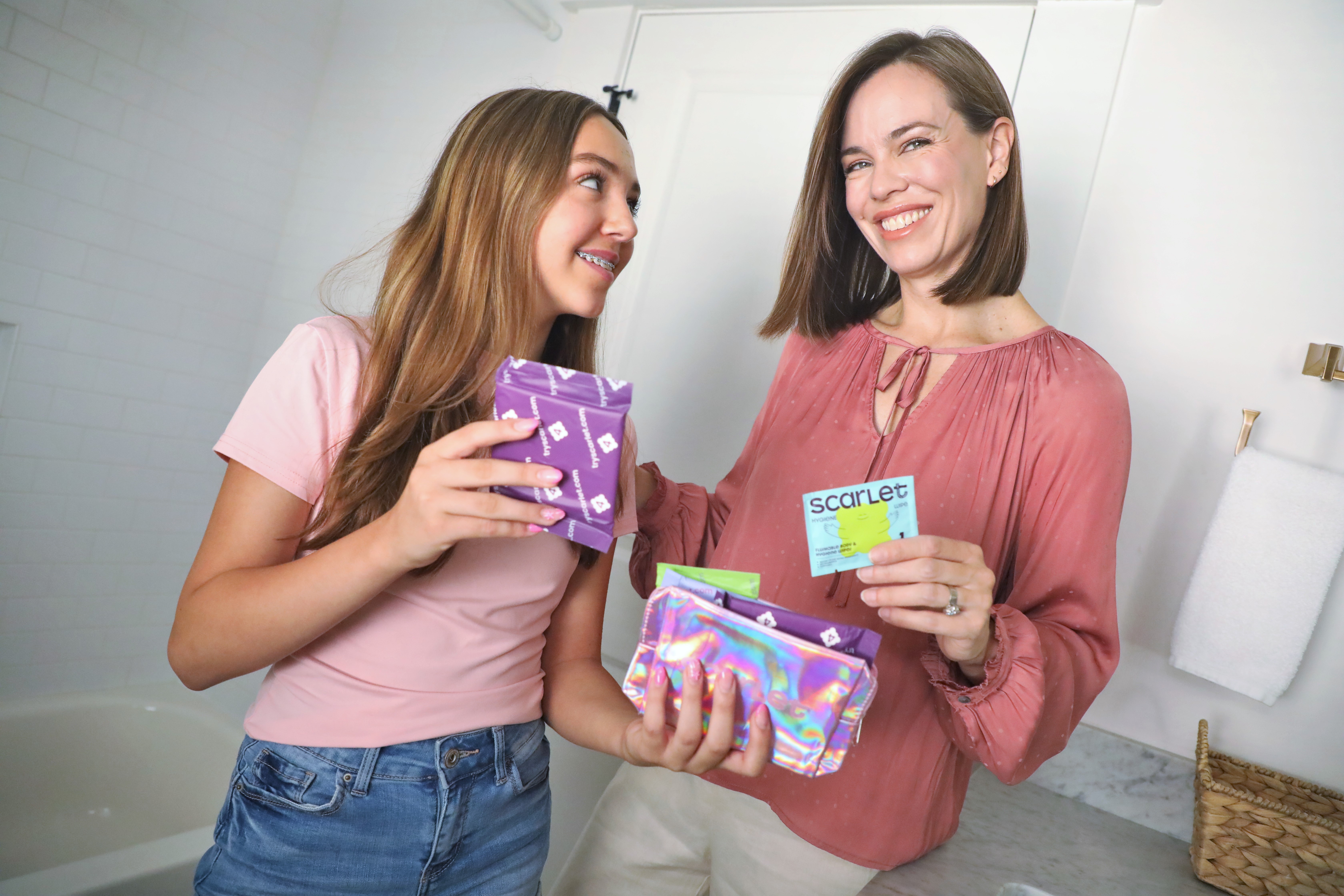 A mom and her tween daughter holding Scarlet Period Kit items together