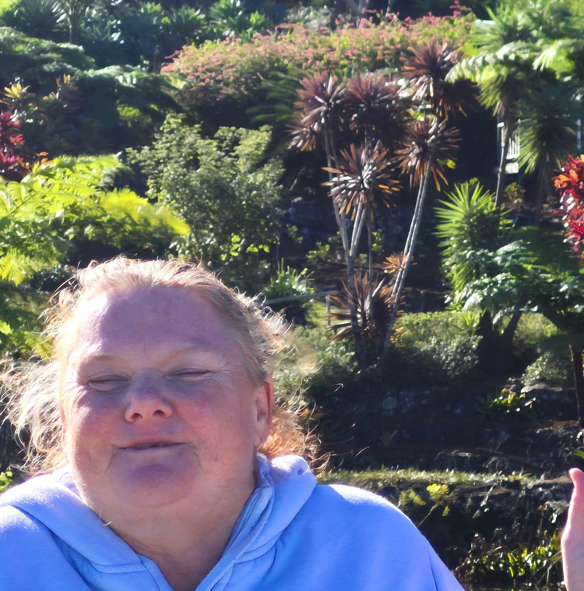 A PeerWave participant smiling in the sunshine among tropical gardens