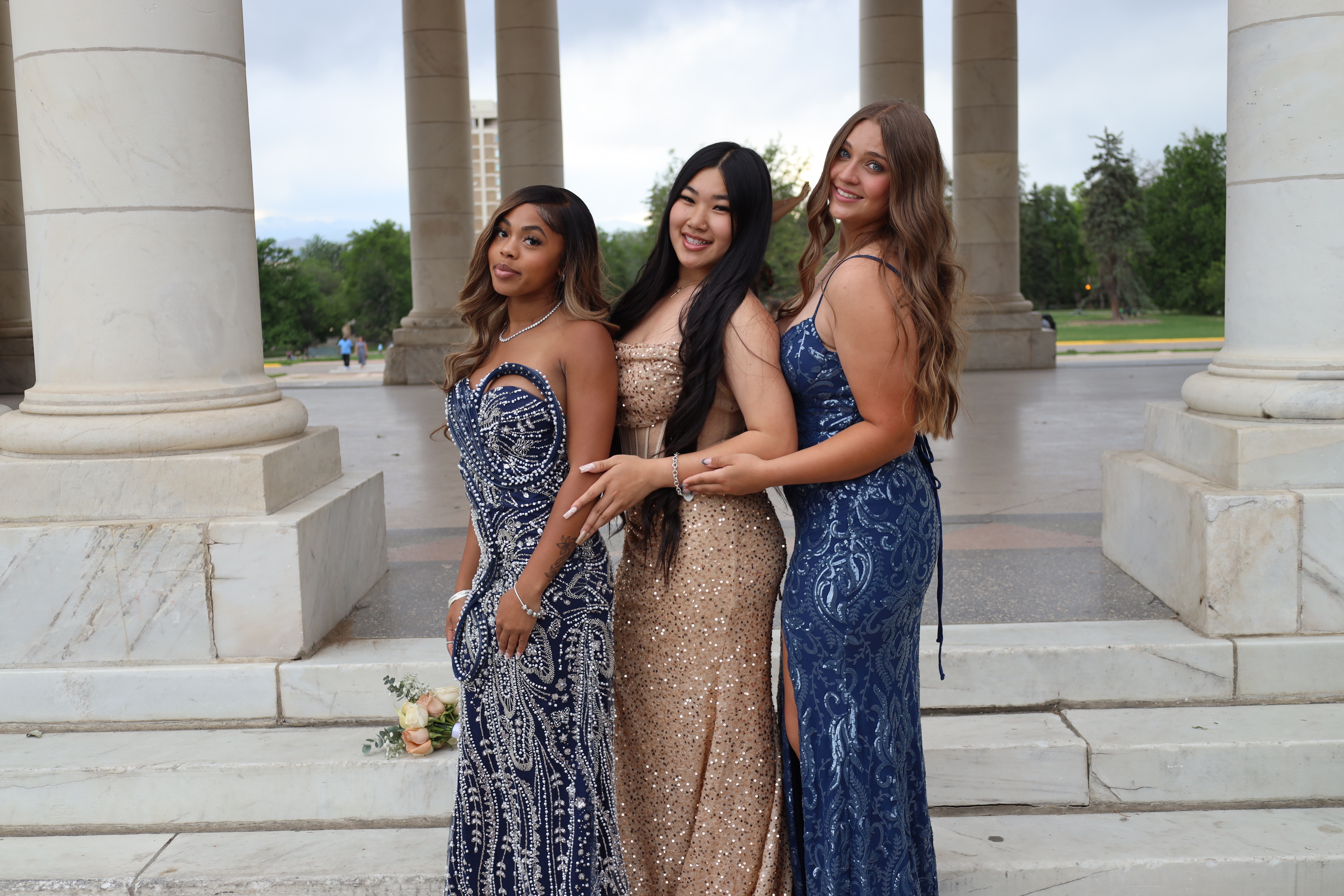 Senior prom trio · navy, gold, and navy gowns at the columns