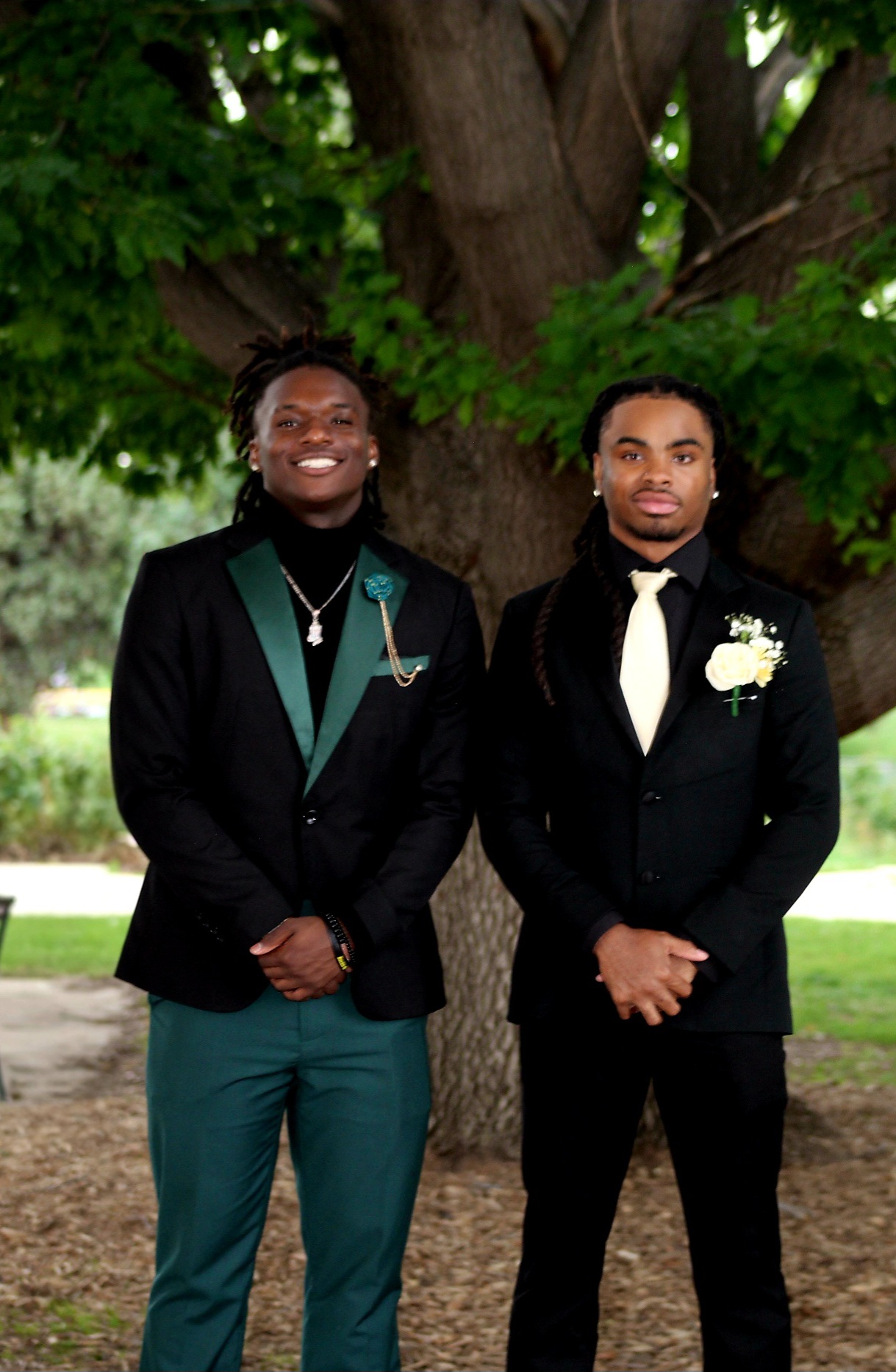 Senior prom · best friends in emerald & black tuxedos under the tree