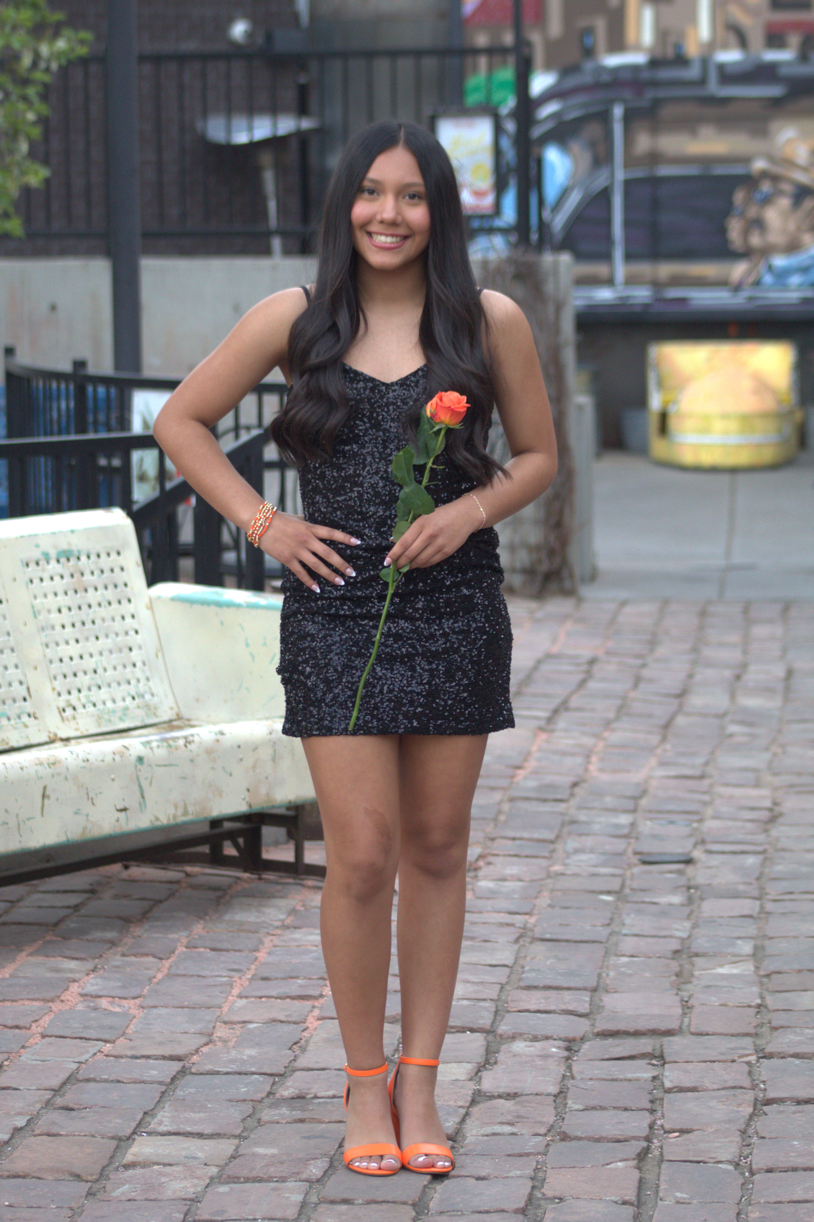 Senior in black sequin dress with rose downtown