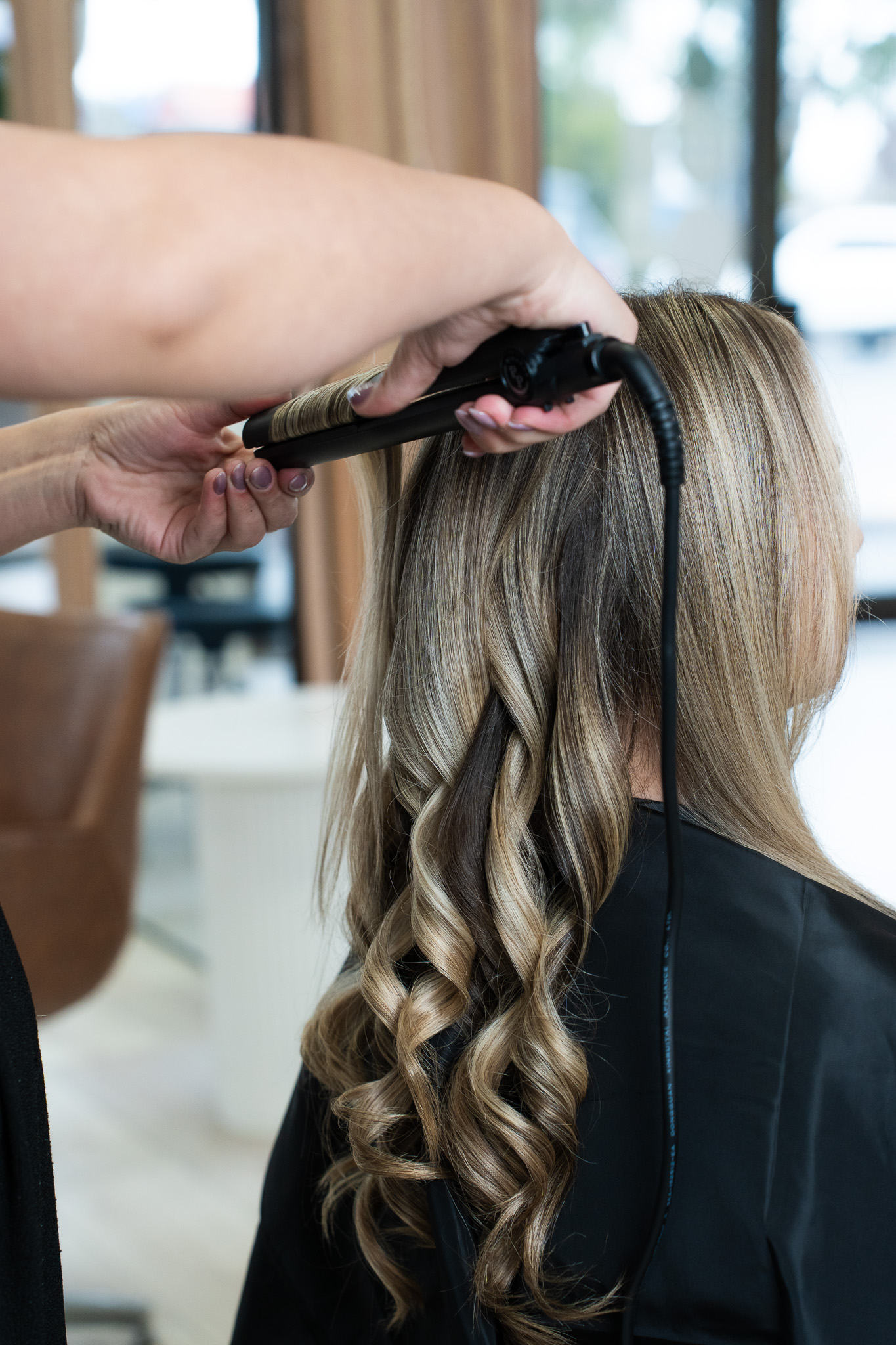 Professional hairdresser creating bouncy curls with Winamor Perfect Pass iron rounded plates - versatile hair styling