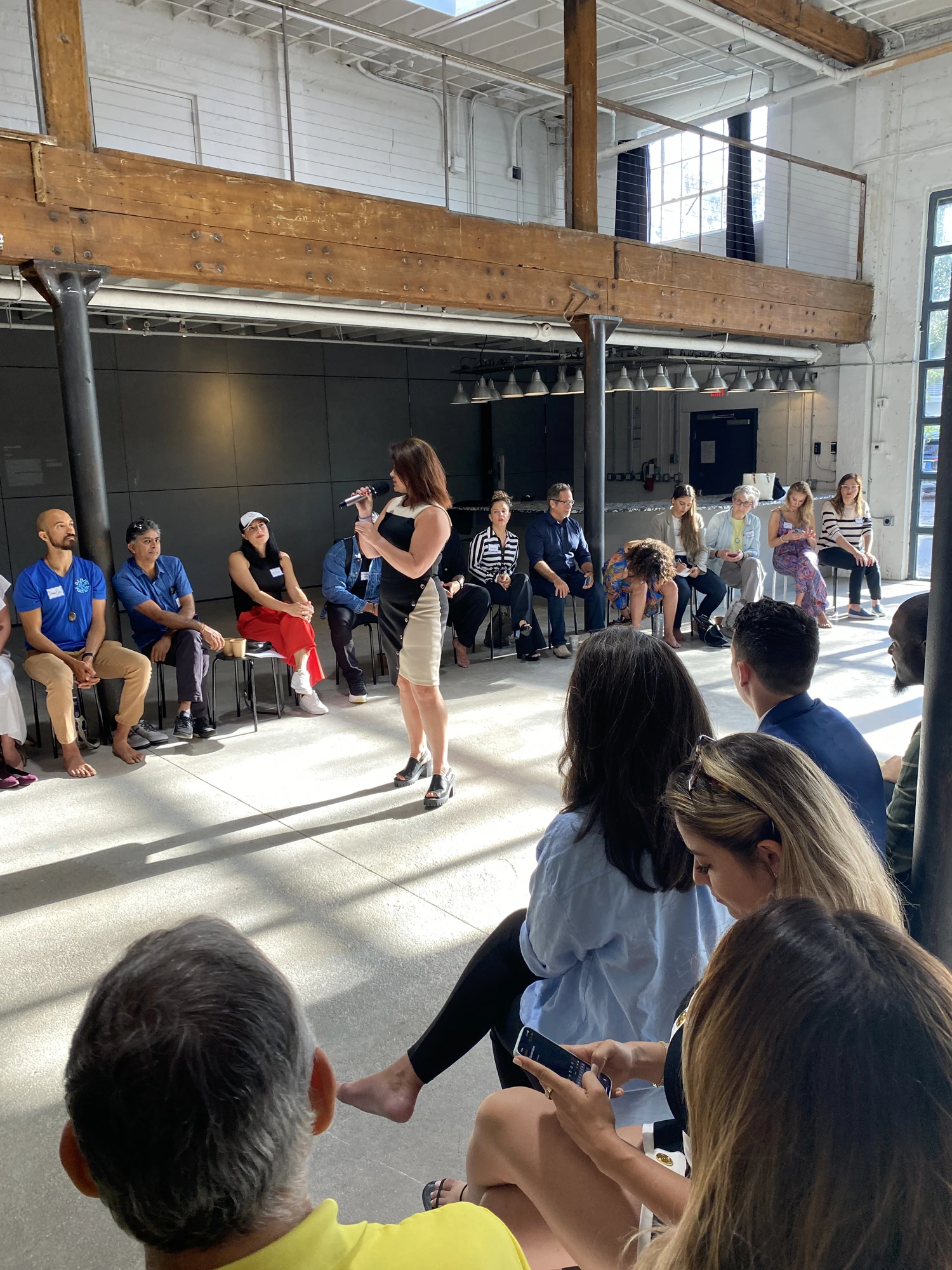 Dr. Crystal Gifford live, in the round — mic in hand with the audience gathered around