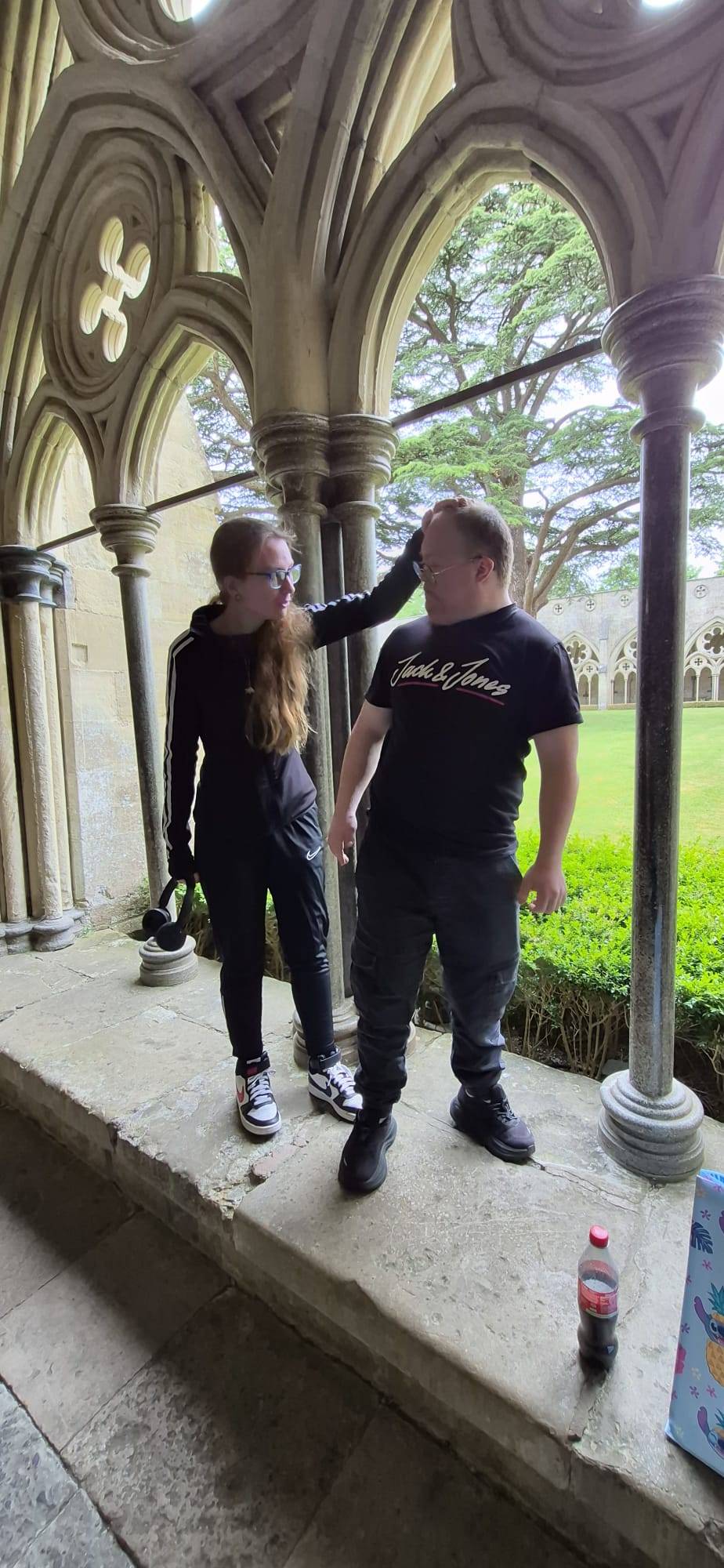 Two people we support sharing a laugh in historic cathedral cloisters.
