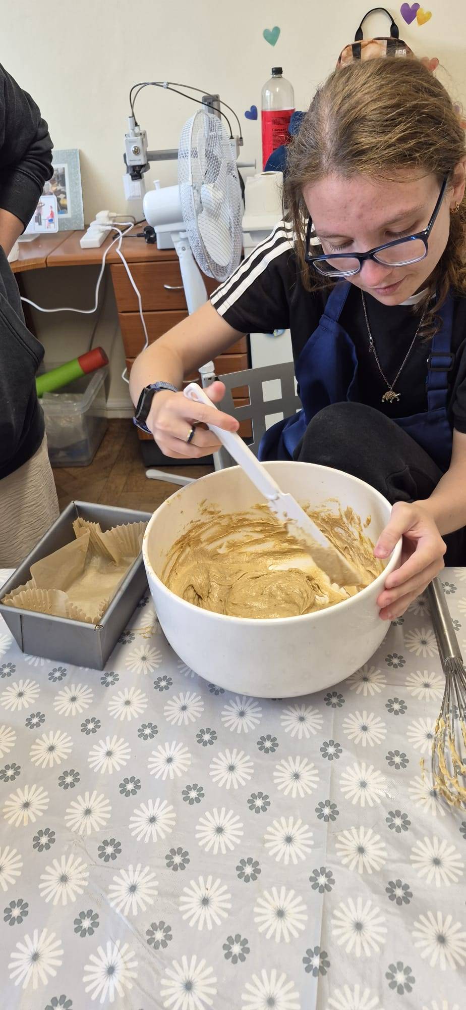 Someone we support carefully mixing cake batter in a bowl during a baking session.
