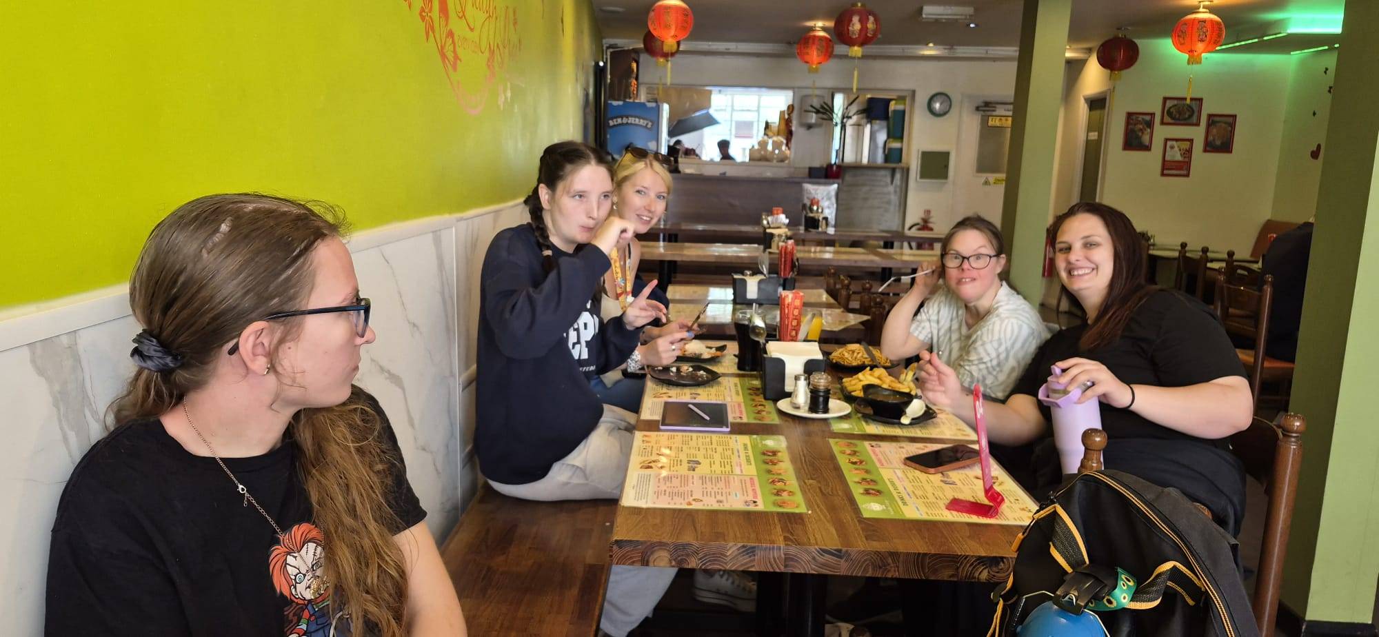 A group of people we support and a support worker enjoying a meal out together at a restaurant.