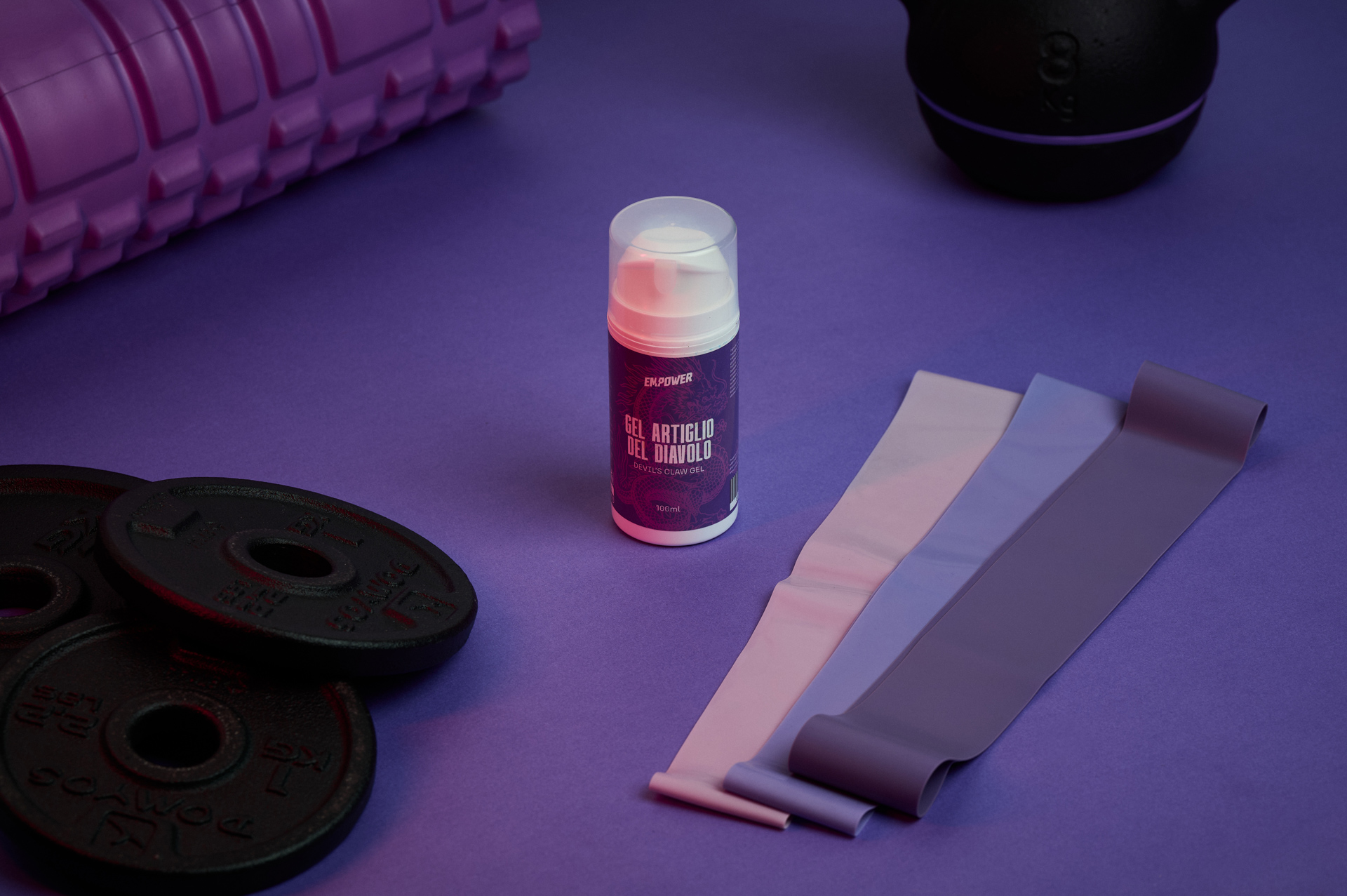 Empower — Gel Artiglio del Diavolo · Packaging Em.Power su scena viola con foam roller, plates e bande di resistenza