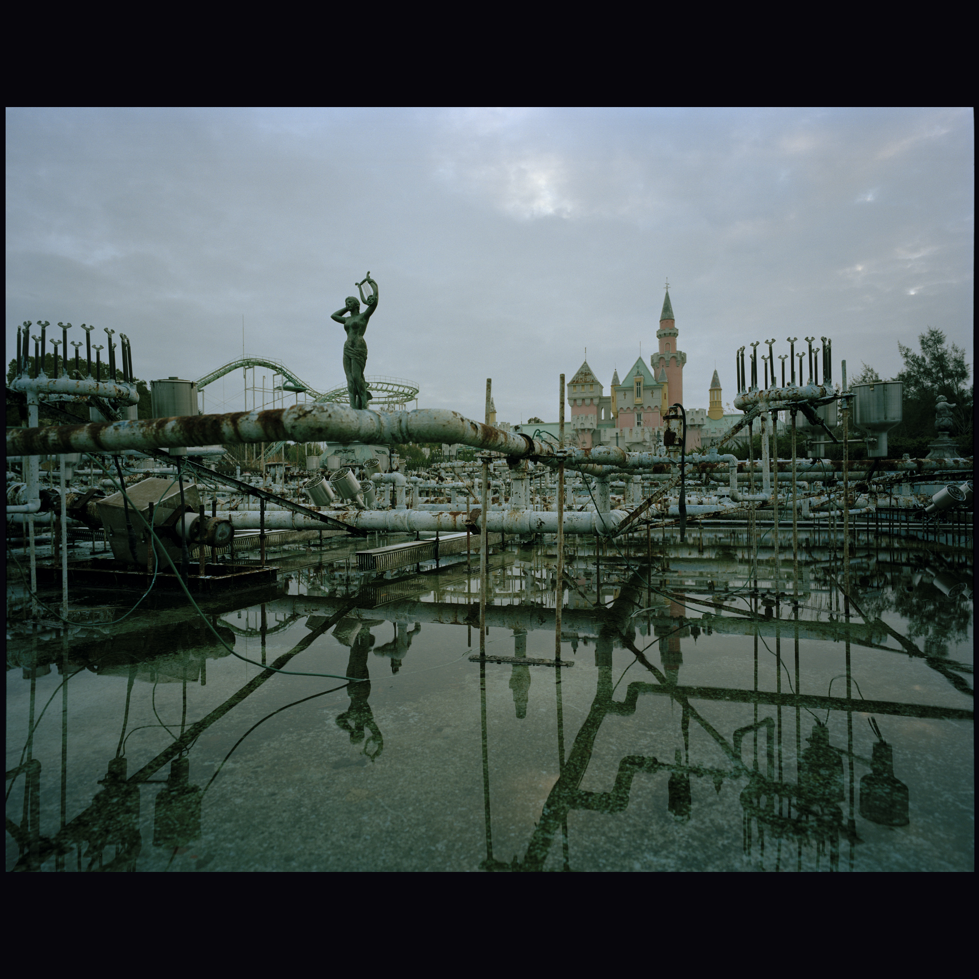 River of Three Crossings — image by Kobi Israel: abandoned park landscape with classical statue, fairy-tale castle and rusted infrastructure reflected in standing water. Details to be confirmed.