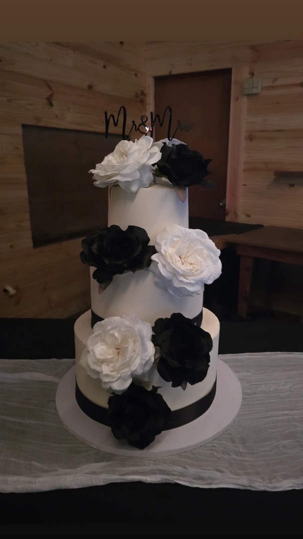 Three-tier white wedding cake with black and ivory roses, Mr & Mrs topper