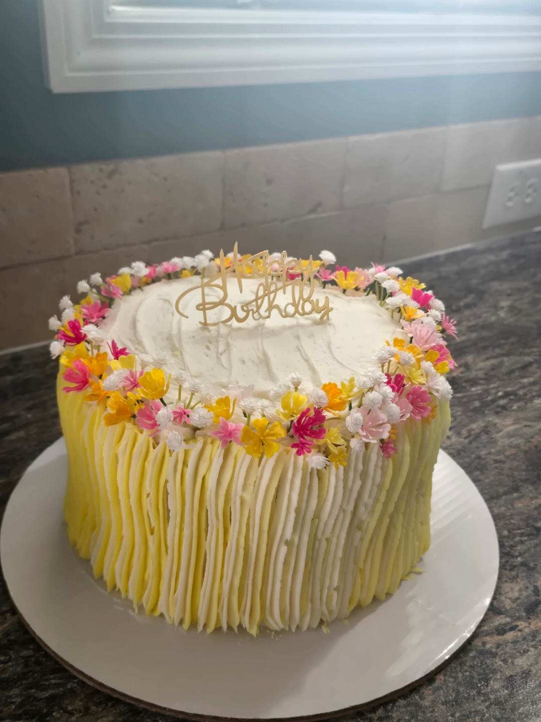 Yellow and white striped buttercream birthday cake with multicolor wildflowers