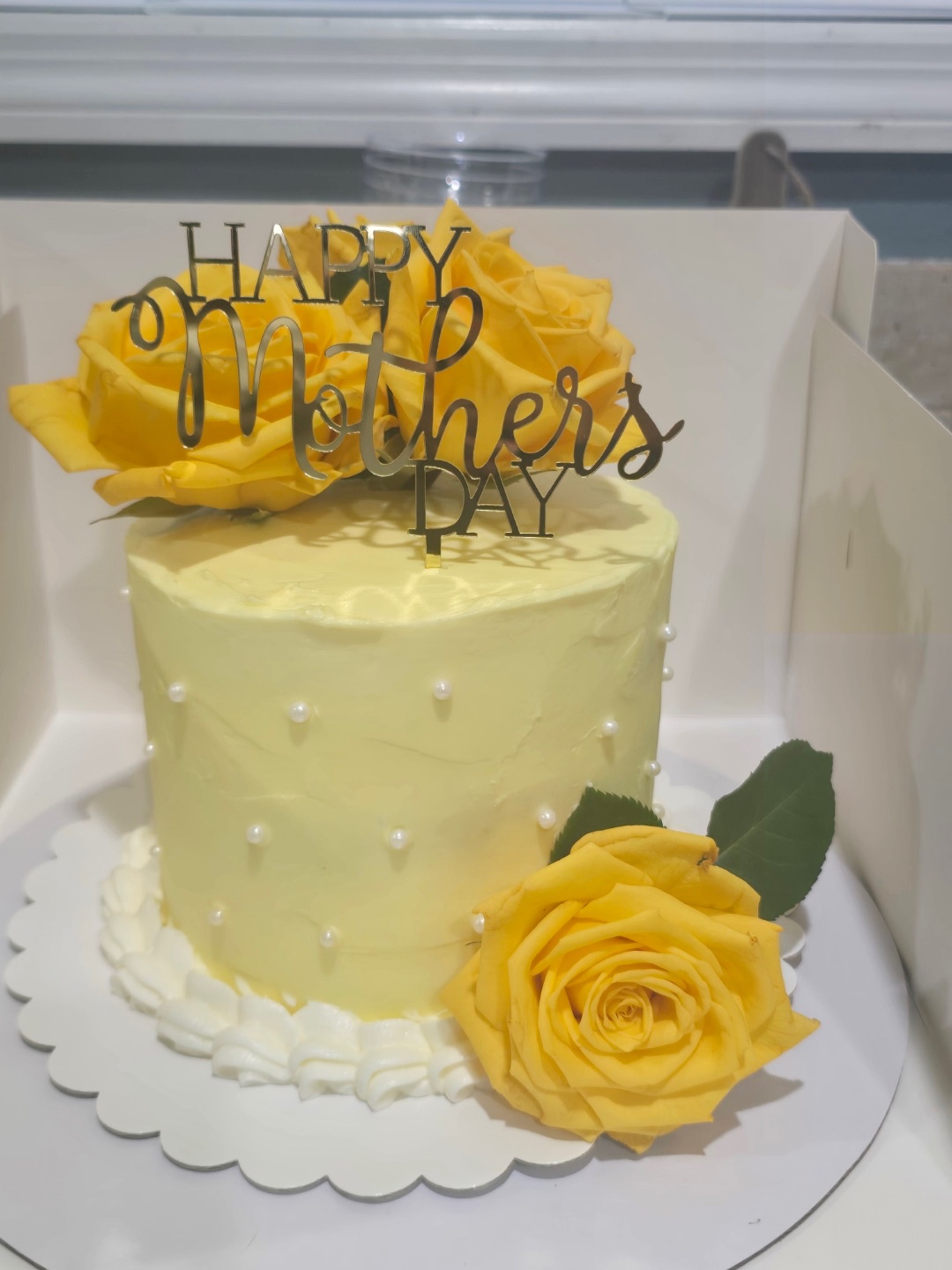 Yellow buttercream Mother’s Day cake with pearls and fresh yellow roses