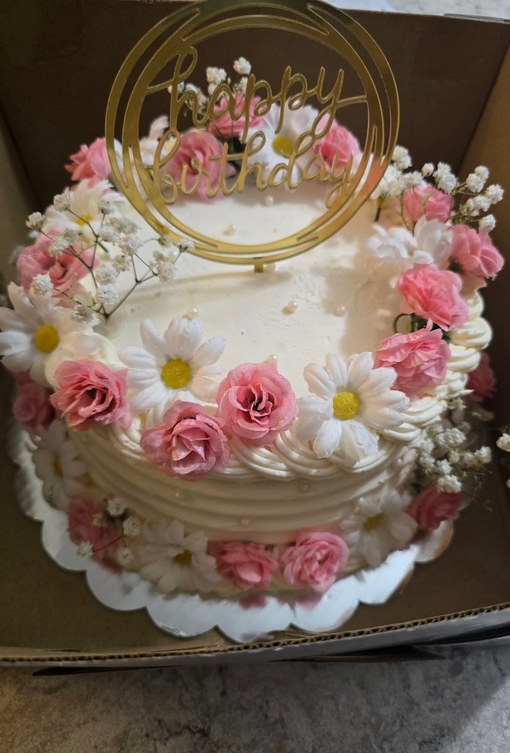 Floral birthday cake with pink roses, daisies, and Happy Birthday topper