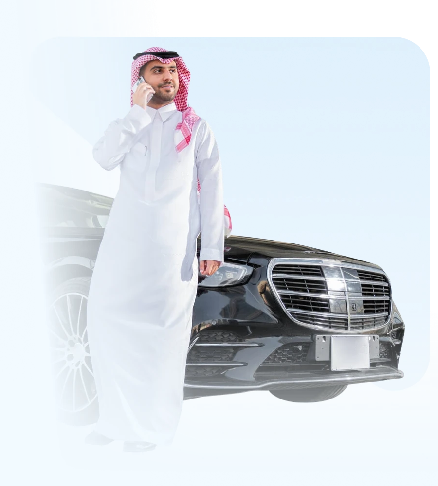 رجل سعودي يتحدث عبر الهاتف بجانب سيارة فاخرة