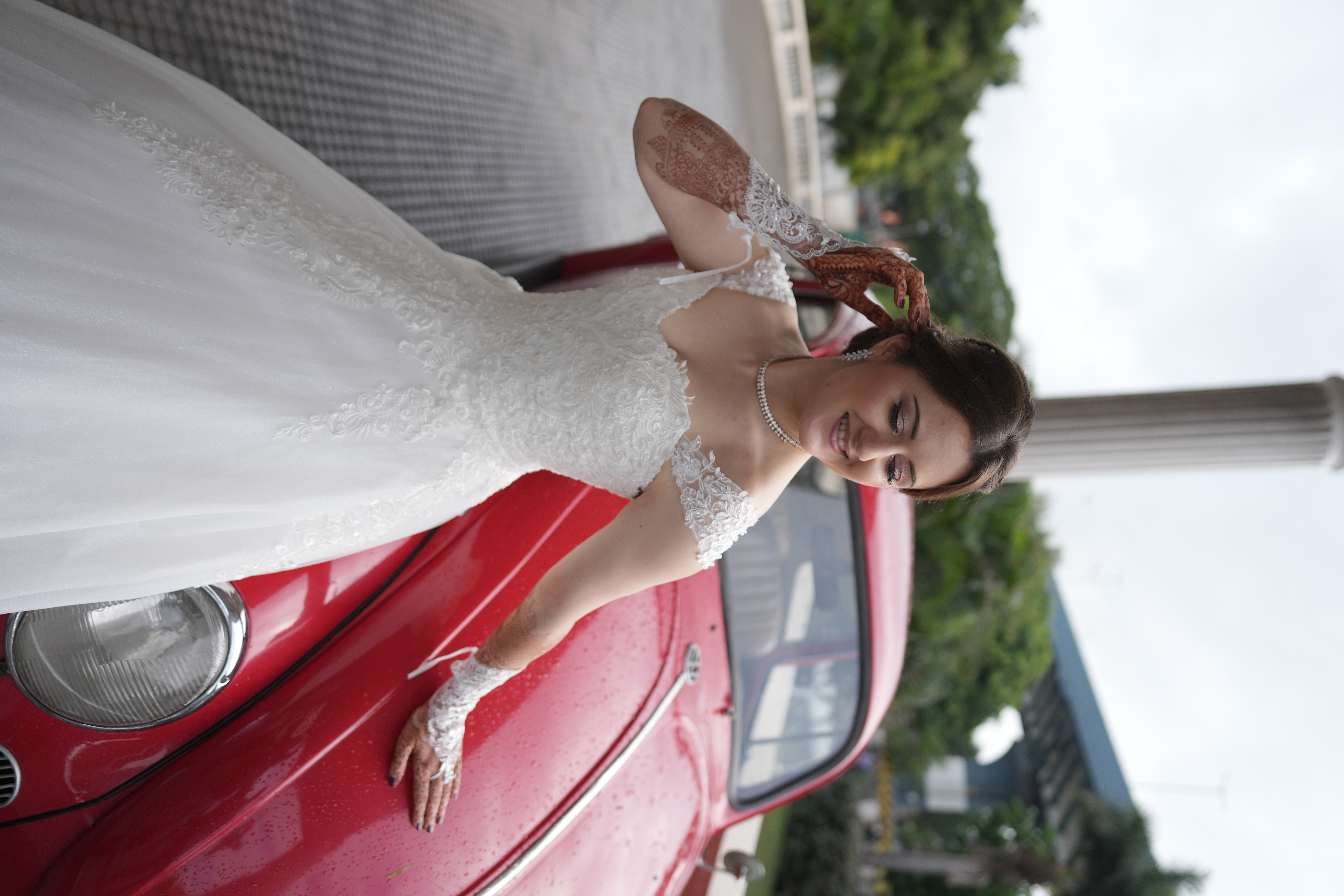 Christian bride in white lace wedding gown with vintage red car — soft glowing HD bridal makeup by La Helen's Coimbatore