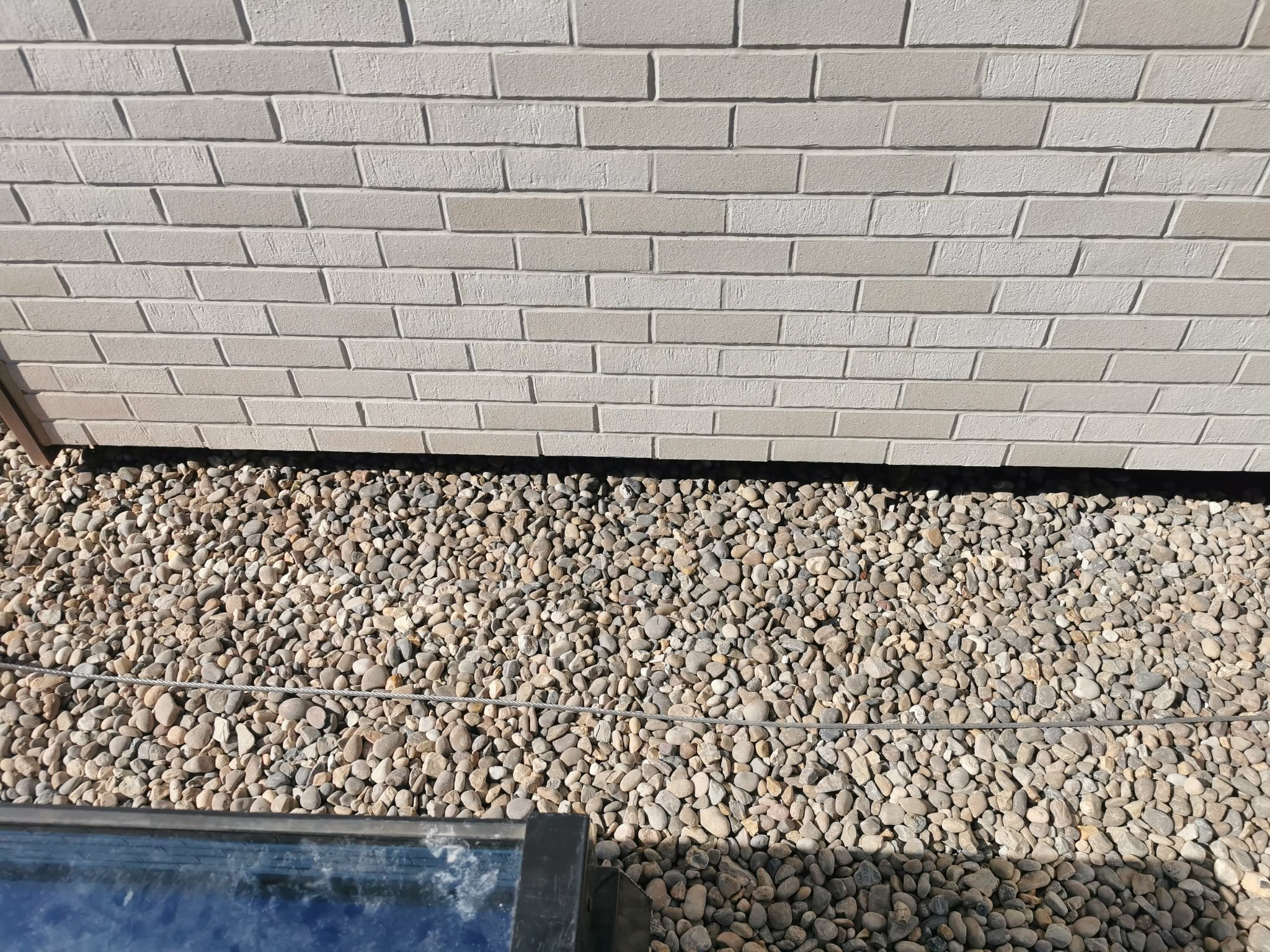 Finished ventilated brick cladding elevation with drainage pebble strip at the base — protects the façade and lets the cavity drain
