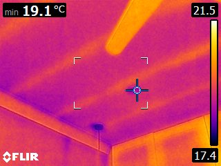 Internal door head and reveal next to a framed picture on a warmer external wall — pronounced cold band along the lintel, prioritised for remedial detailing in the costed report