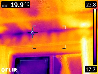 Wall / ceiling junction with door head — significant cold band along the lintel and reveal, classic thermal-bridge pattern combined with air leakage