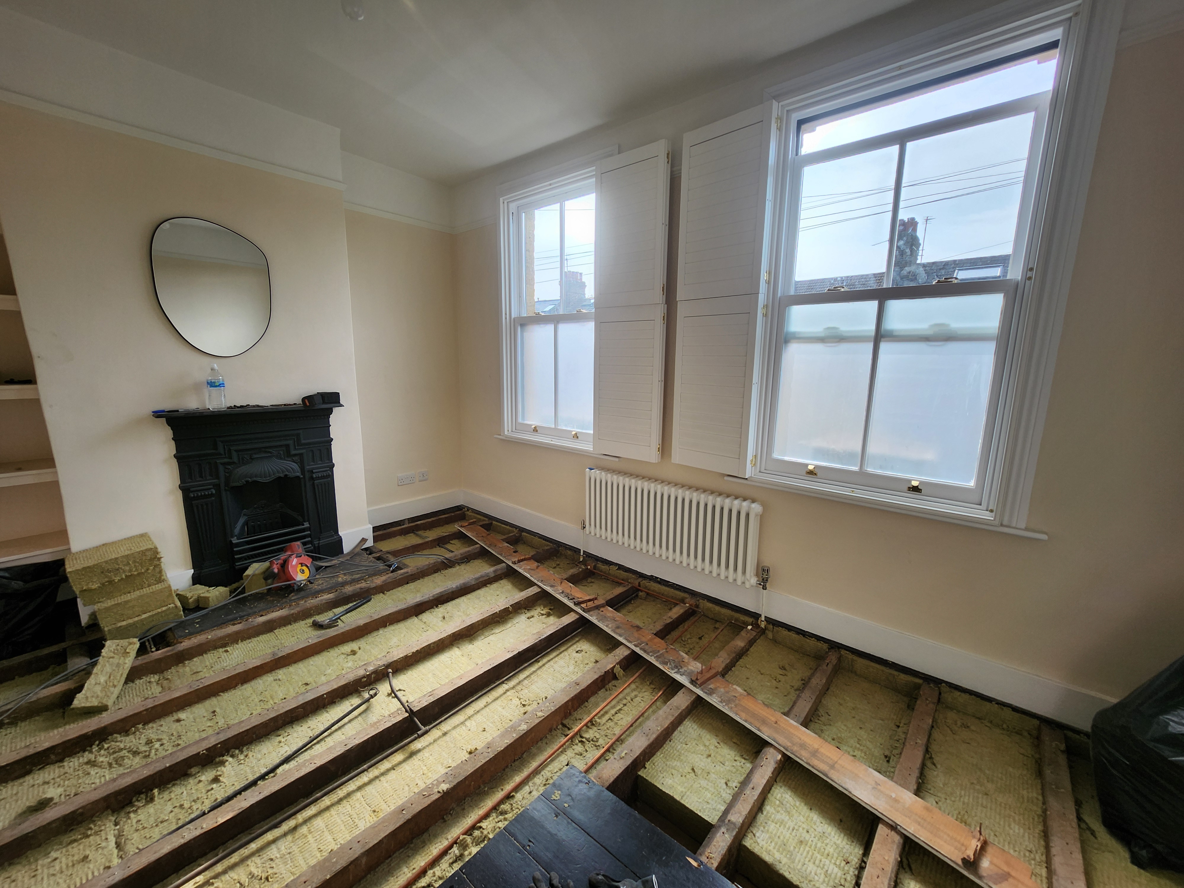 Stage 2 — mineral wool acoustic insulation being placed between the joists to absorb airborne noise