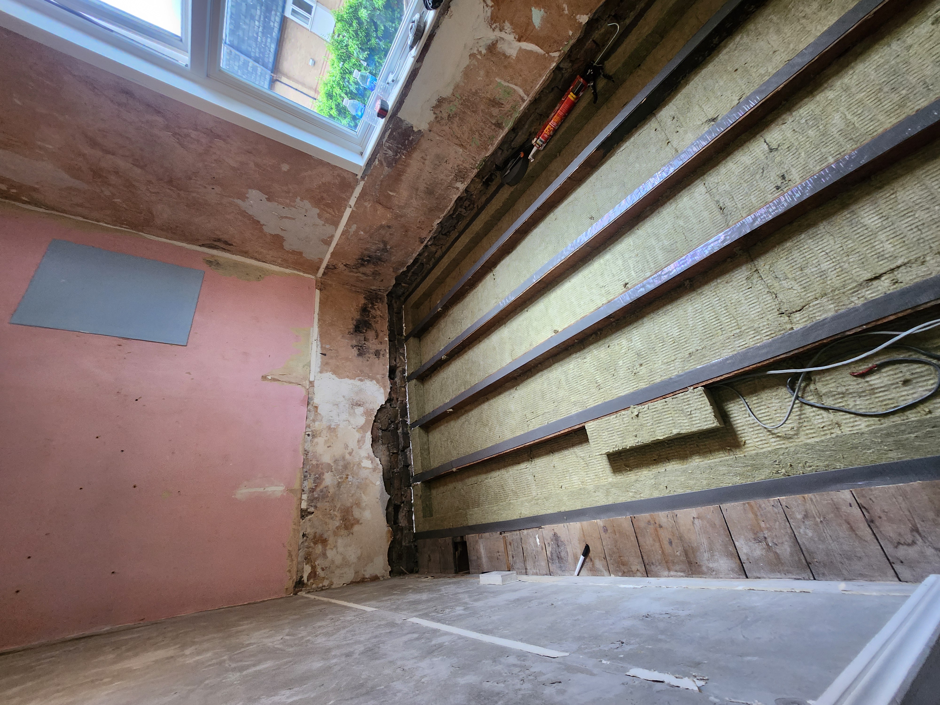 N17 project · pink bedroom — existing floor finishes removed, joists exposed, RW5 acoustic mineral wool installed between joists with resilient bars laid across