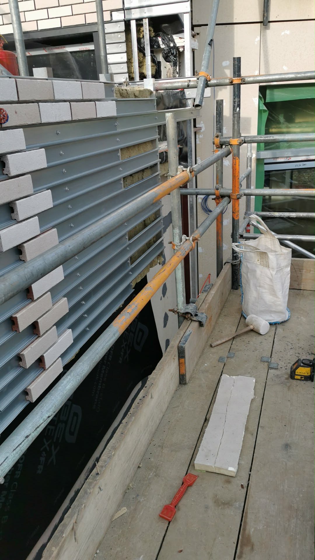 Brick-slip cladding installed onto the panel system with fresh mortar pointing — corner detail showing crisp alignment